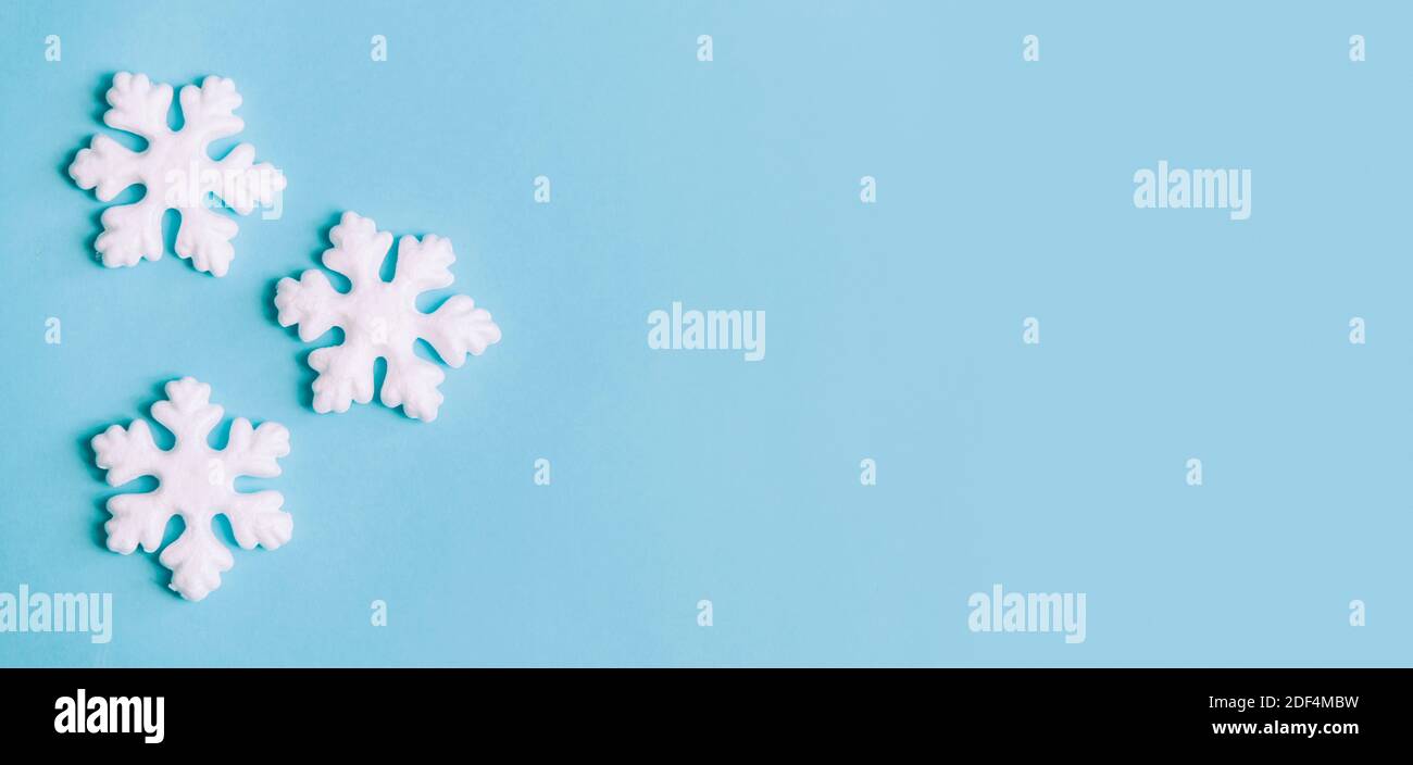 Composition minimale pour noël, nouvel an et vacances d'hiver. Pose à plat. Bannière créative avec flocons de neige sur fond bleu pastel. Noël et hiver Banque D'Images