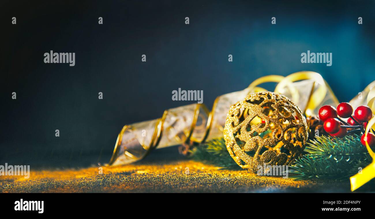 Boule d'ornement de chrismtas doré avec sapin et ruban d'or sur fond de paillettes de bokeh foncé. Carte de vœux du nouvel an. Célébration de luxe Banque D'Images