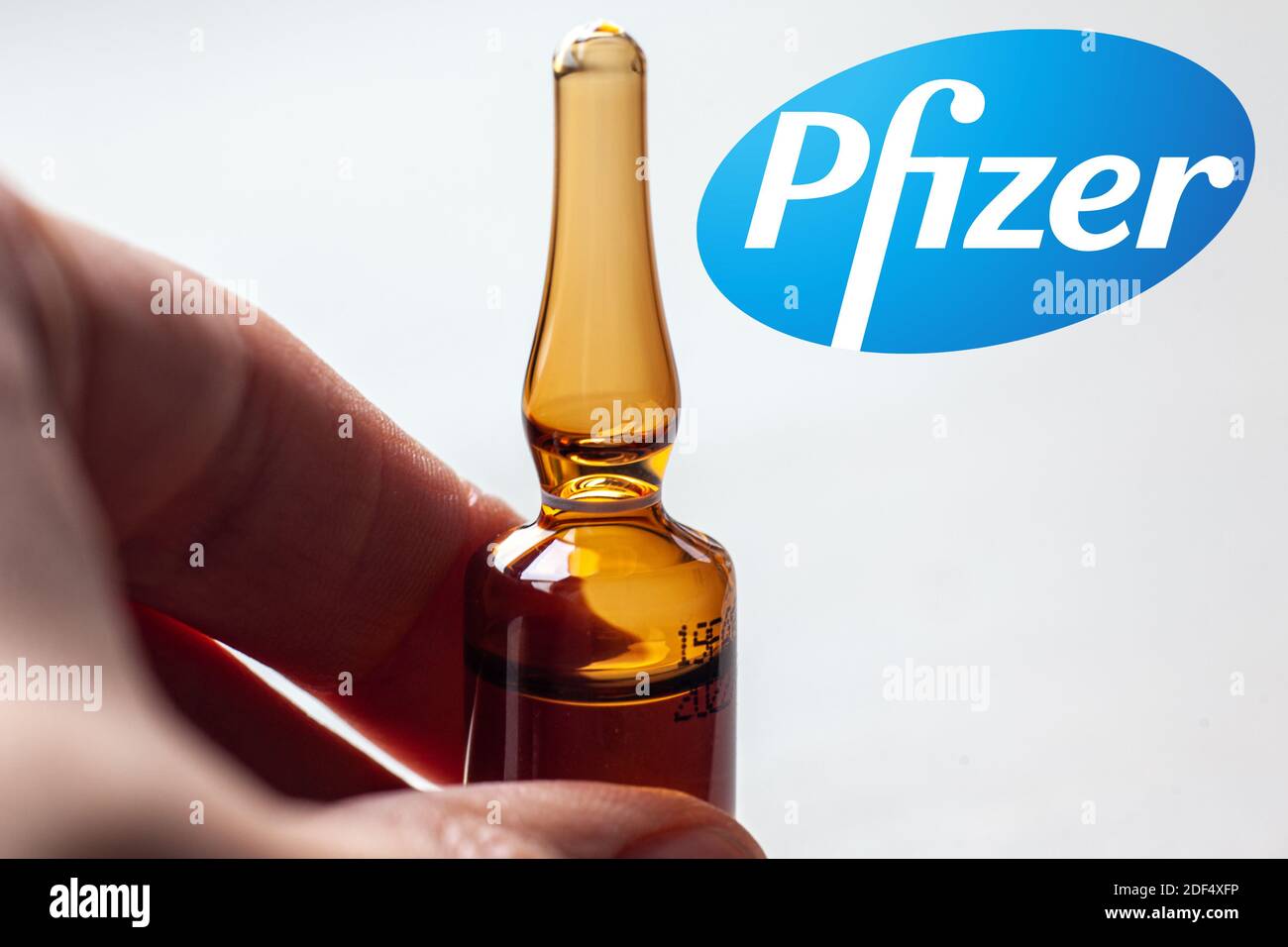 Société pharmaceutique Pfizer de vaccins contre le coronavirus. Logo Pfizer avec main tenant le nouveau vaccin. Banque D'Images