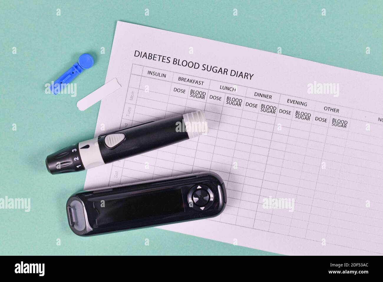 Journal de glycémie pour le diabète avec glucomètre, lancettes, bandes de tests et dispositif de lancing sur fond vert Banque D'Images