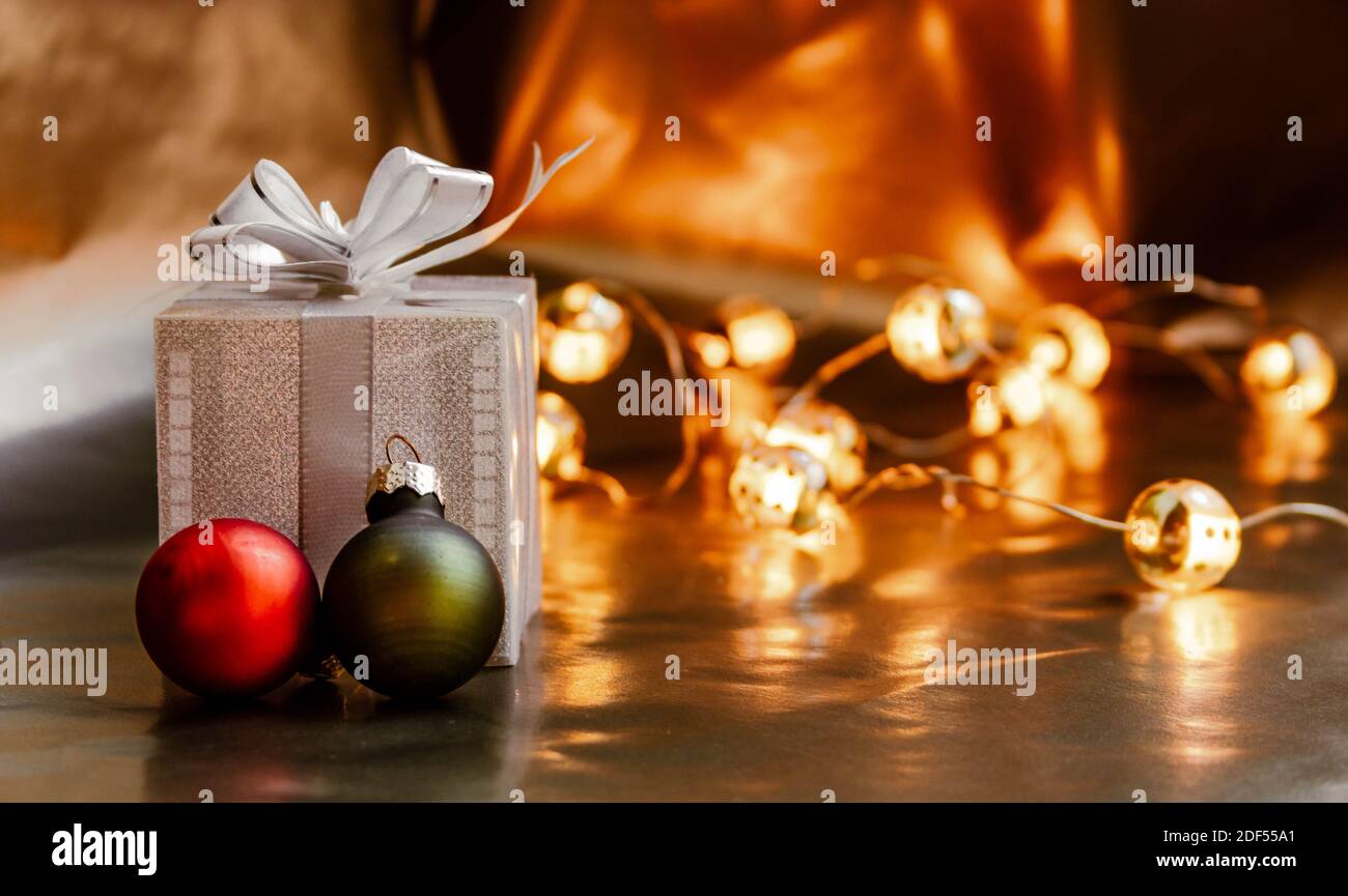 Petite boîte cadeau avec boules de Noël orange et vertes en premier plan et lumières de Noël bokeh en arrière-plan. Banque D'Images