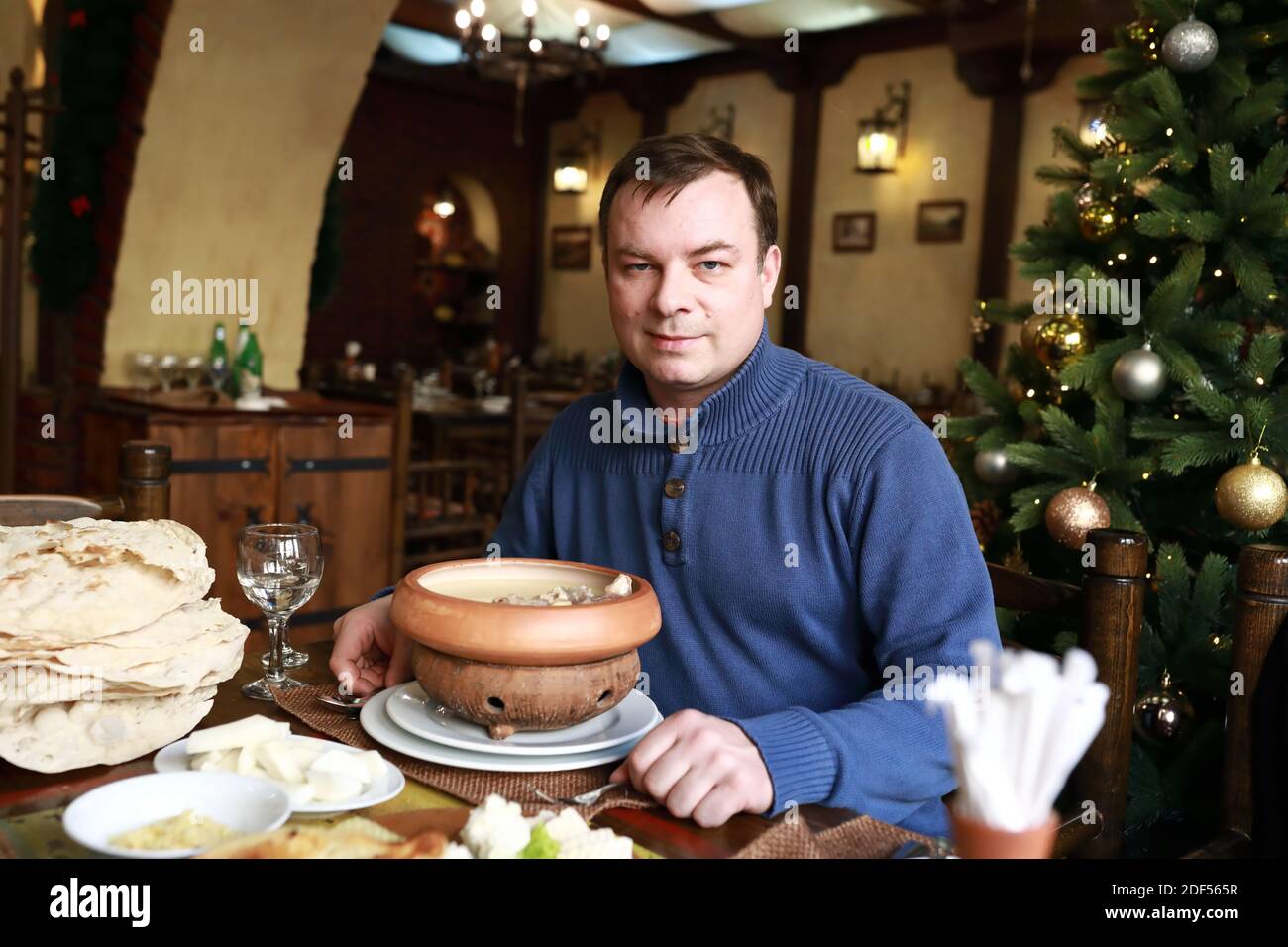 Homme posant avec un bol de khash au restaurant Banque D'Images