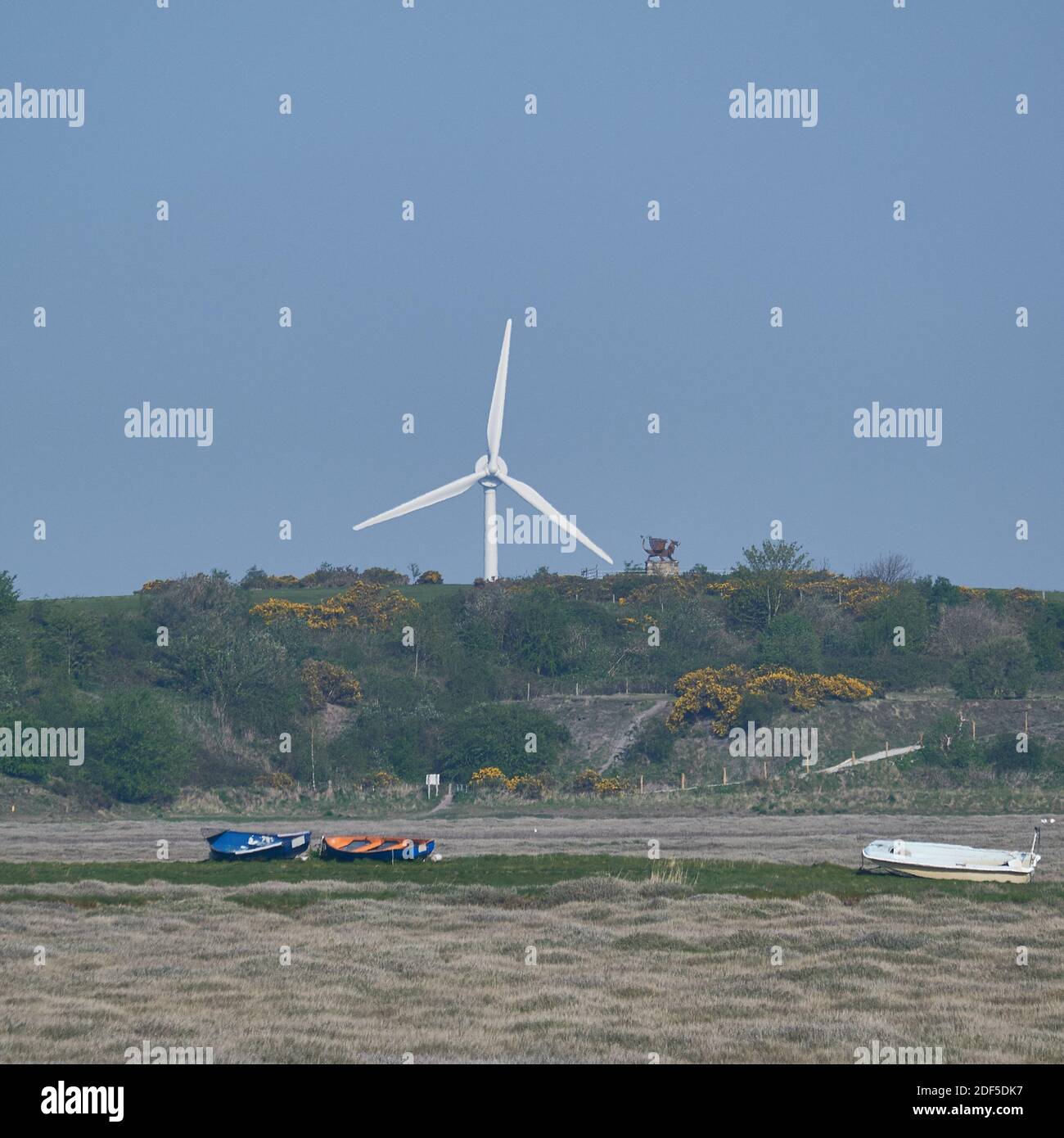 Le Jubilee Dragon Beacon et une éolienne géante se tiennent au-dessus des bateaux encachés sur les marécages de Bagillt, Flintshire. Banque D'Images