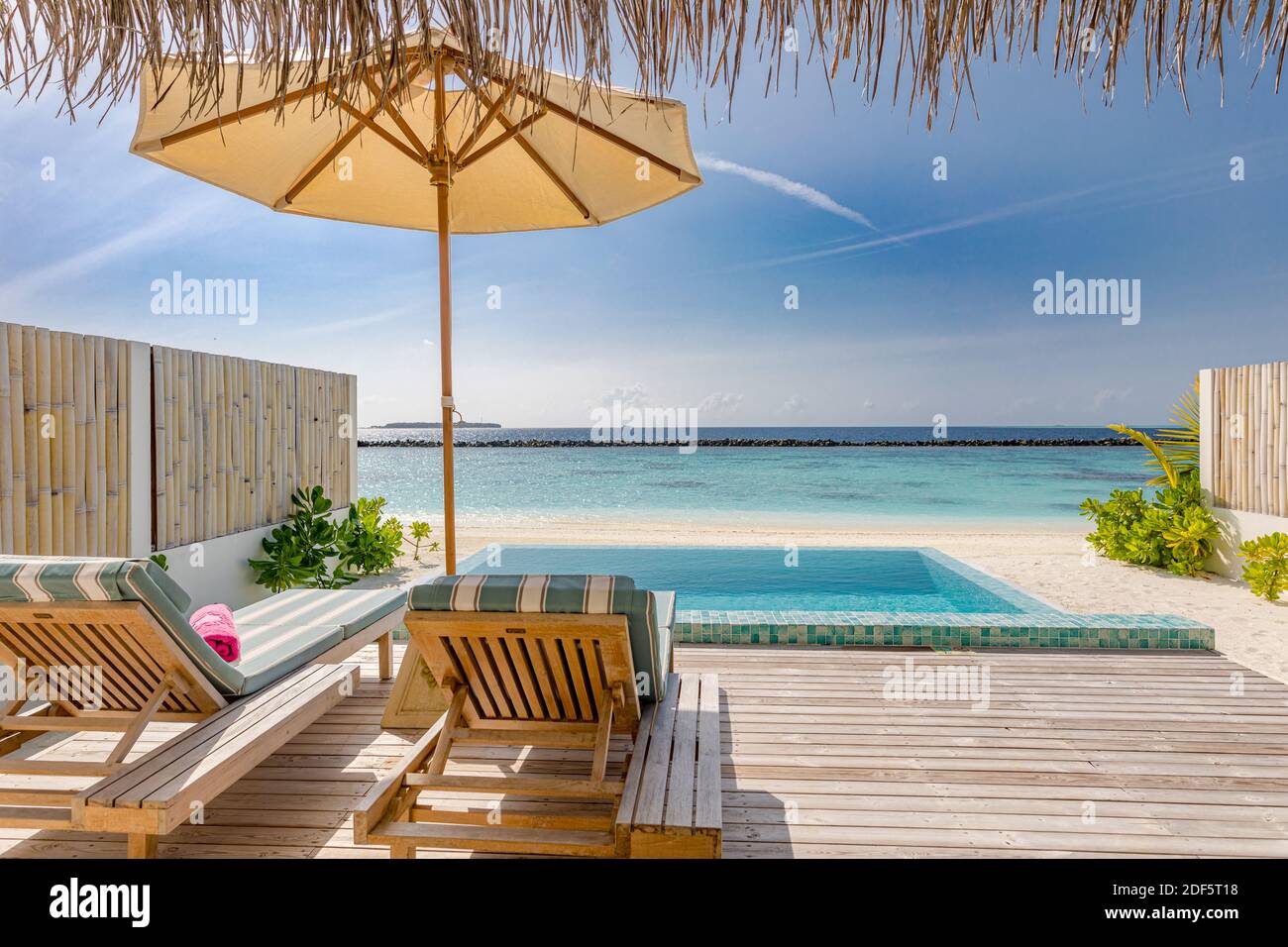 Station balnéaire de luxe. Piscine et chaises de plage sous parasol. Voyage et vacances sur l'île d'été, paysage marin. Villa d'eau Maldive Banque D'Images