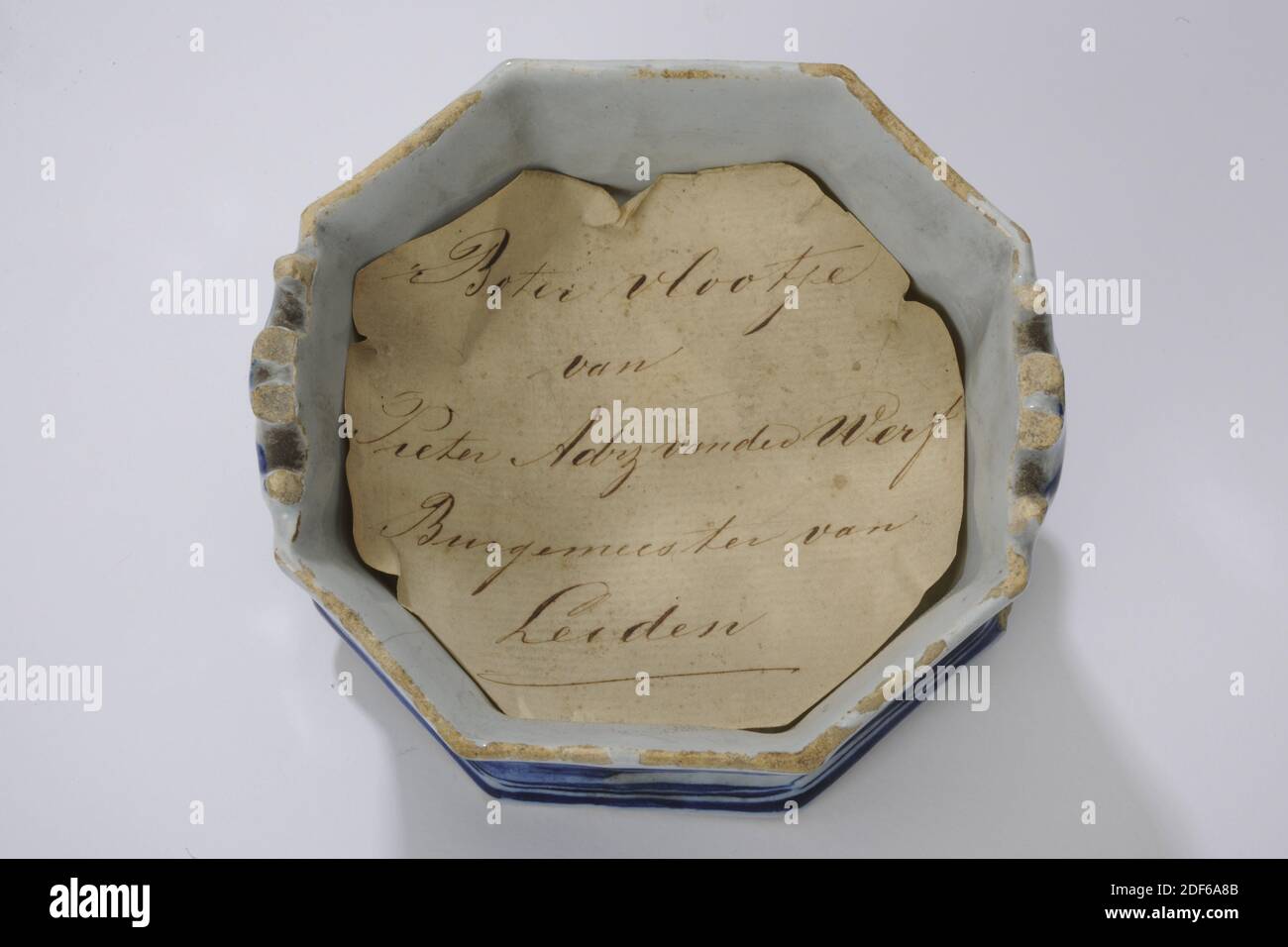 Plat à beurre, Anonyme, XVIIIe siècle, encre, papier, glaçure, faïence, plat à beurre avec couvercle : 7.8 x 11.1 x 11,1 cm 78 x 111 x 111 mm, Pot : 5.1 x 11.1 x 10,3 cm 51 x 111 x 103 mm, couvercle : 3.6 x 9.9 x 11,2 cm 36 x 99 x 11mm, paysage, bâtiment, arbre, plat à beurre en faïence bleue de Delft, octogonal, décoré d'un paysage chinois. Le paysage montre des collines, un arbre et une structure. Avec un couvercle qui dépeint également un paysage, composé d'un bâtiment et d'arbres. Dans le plat à beurre un morceau de papier coupé à la taille avec écrit sur lui dans l'encre: Le plat à beurre par Pieter Adrz. Van der Werf Maire de Leiden Banque D'Images Plat à beurre, Anonyme, XVIIIe siècle, encre, papier, glaçure, faïence, plat à beurre avec couvercle : 7.8 x 11.1 x 11,1 cm 78 x 111 x 111 mm, Pot : 5.1 x 11.1 x 10,3 cm 51 x 111 x 103 mm, couvercle : 3.6 x 9.9 x 11,2 cm 36 x 99 x 11mm, paysage, bâtiment, arbre, plat à beurre en faïence bleue de Delft, octogonal, décoré d'un paysage chinois. Le paysage montre des collines, un arbre et une structure. Avec un couvercle qui dépeint également un paysage, composé d'un bâtiment et d'arbres. Dans le plat à beurre un morceau de papier coupé à la taille avec écrit sur lui dans l'encre: Le plat à beurre par Pieter Adrz. Van der Werf Maire de Leiden Banque D'Images
