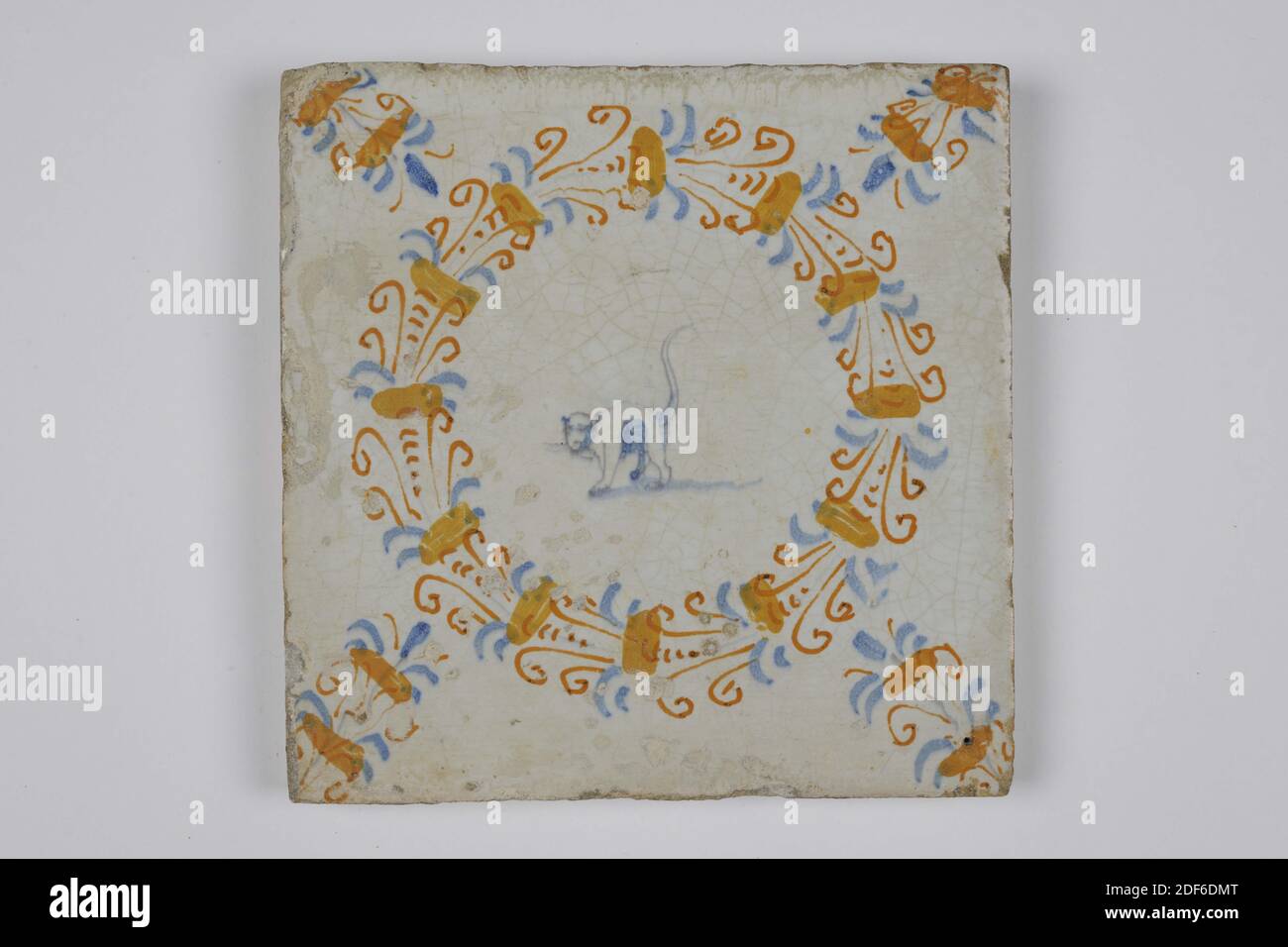 Tuile murale, Anonyme, première moitié du XVIIe siècle, glaçure d'étain, faïence, général : 12.7 x 12.8 x 1,3cm (127 x 128 x 13mm), chat, pays-Bas du nord, tuile de poterie d'Haarlem recouverte de glaçure d'étain. Peinture multicolore en bleu, jaune, orange et violet avec tirage violet. La tuile représente un chat dans une couronne d'aigrette. La tuile a un motif d'aigrette comme un coin, 1985 Banque D'Images