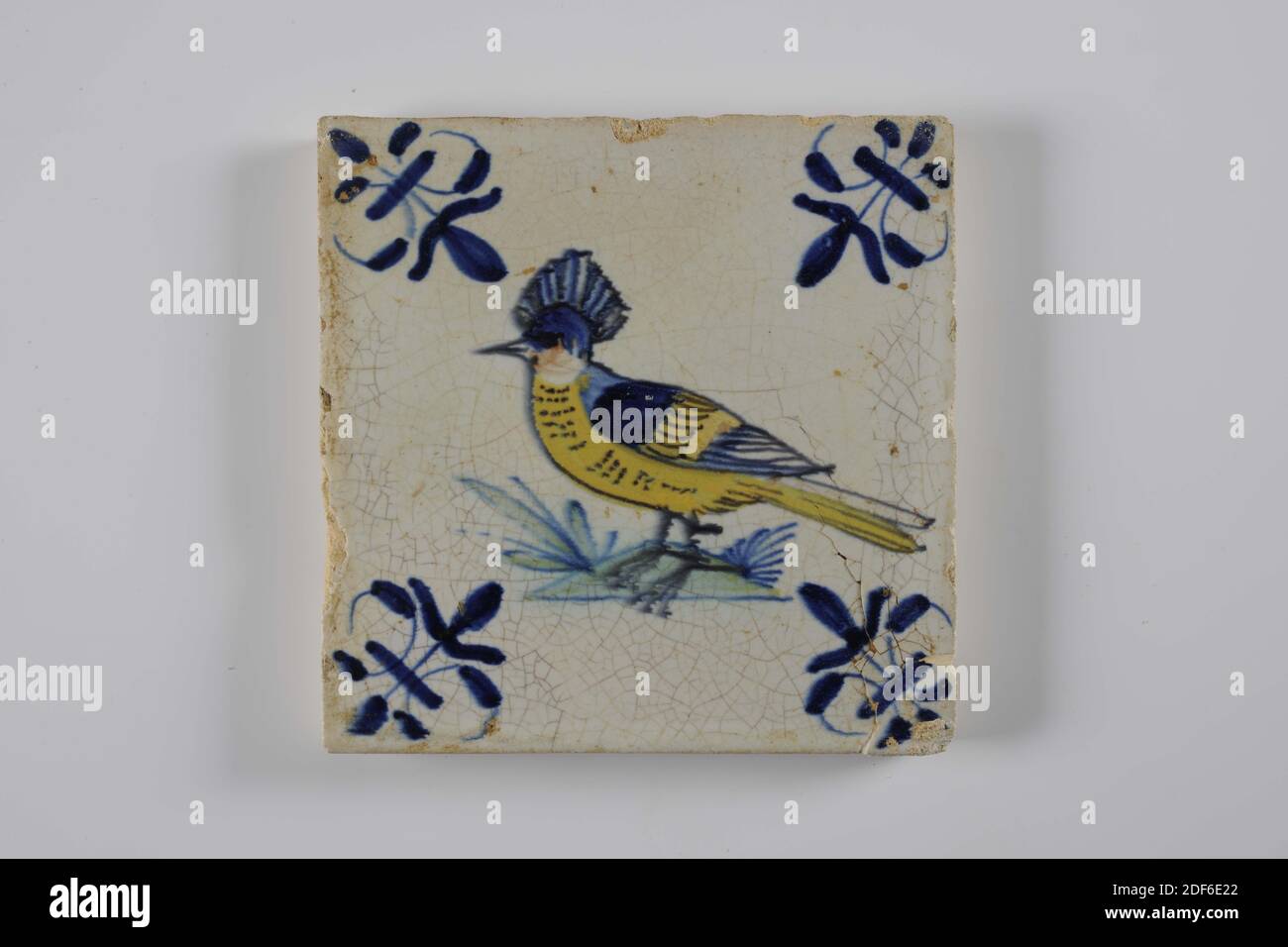 Carreau de mur, Anonyme, entre 1620-1650, glaçure d'étain, faïence, général: 13 x 13 x 1,2cm (130 x 130 x 12mm), oiseau, gouda, carreau de mur de faïence recouvert de glaçure d'étain. La tuile est peinte multicolore en vert, bleu et jaune. La tuile représente un oiseau orienté vers la gauche avec une crête sur un sol. La tuile a un lis comme un motif de coin, 1995 Banque D'Images