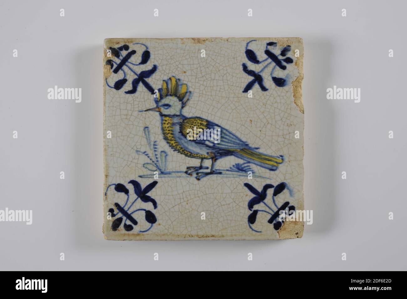 Carreau de mur, Anonyme, entre 1620-1650, glaçure d'étain, faïence, général: 13 x 13 x 1,2cm (130 x 130 x 12mm), oiseau, gouda, carreau de mur de faïence recouvert de glaçure d'étain. La tuile est peinte multicolore en vert, bleu et jaune. La tuile représente un oiseau orienté vers la gauche avec une crête sur un sol. La tuile a un lis comme un motif de coin, 1995 Banque D'Images