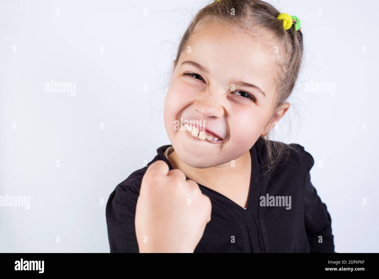 Une fille en colère avec un grin menace avec un poing sur un fond blanc. Banque D'Images