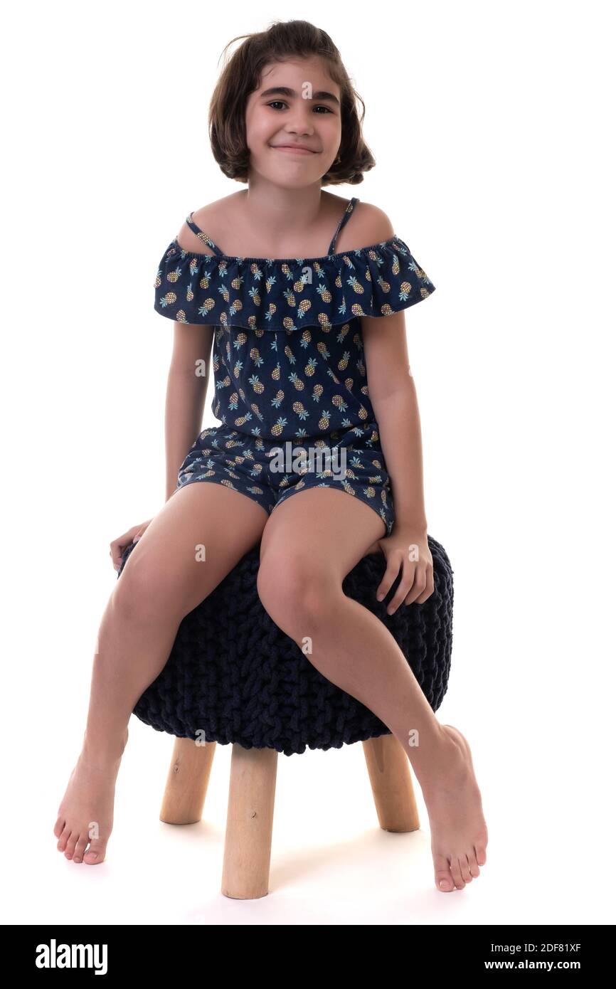 Jolie fille hispanique assise sur un tabouret - isolée sur fond blanc Banque D'Images