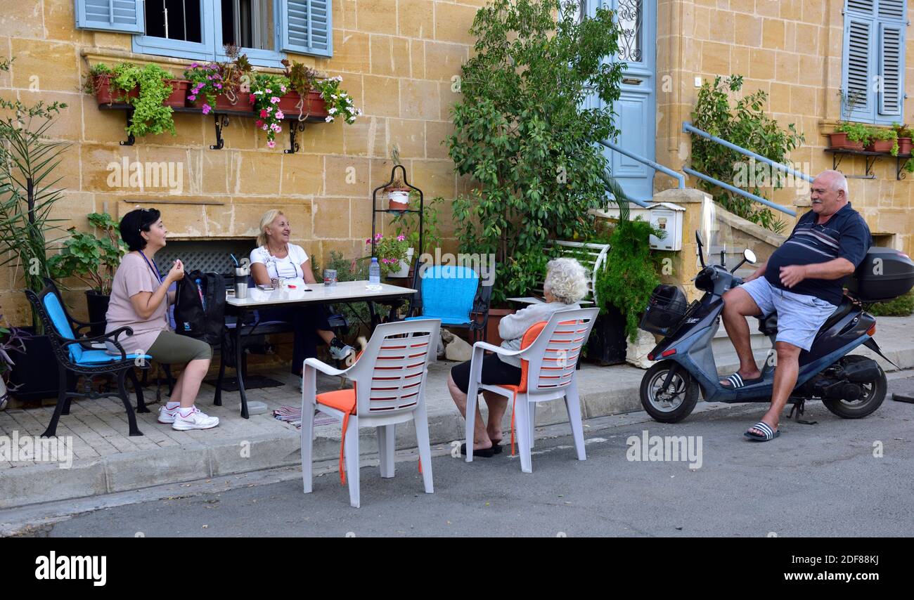 Des amis, des voisins se rencontrent pour discuter autour de la table sur le trottoir à l'extérieur Banque D'Images