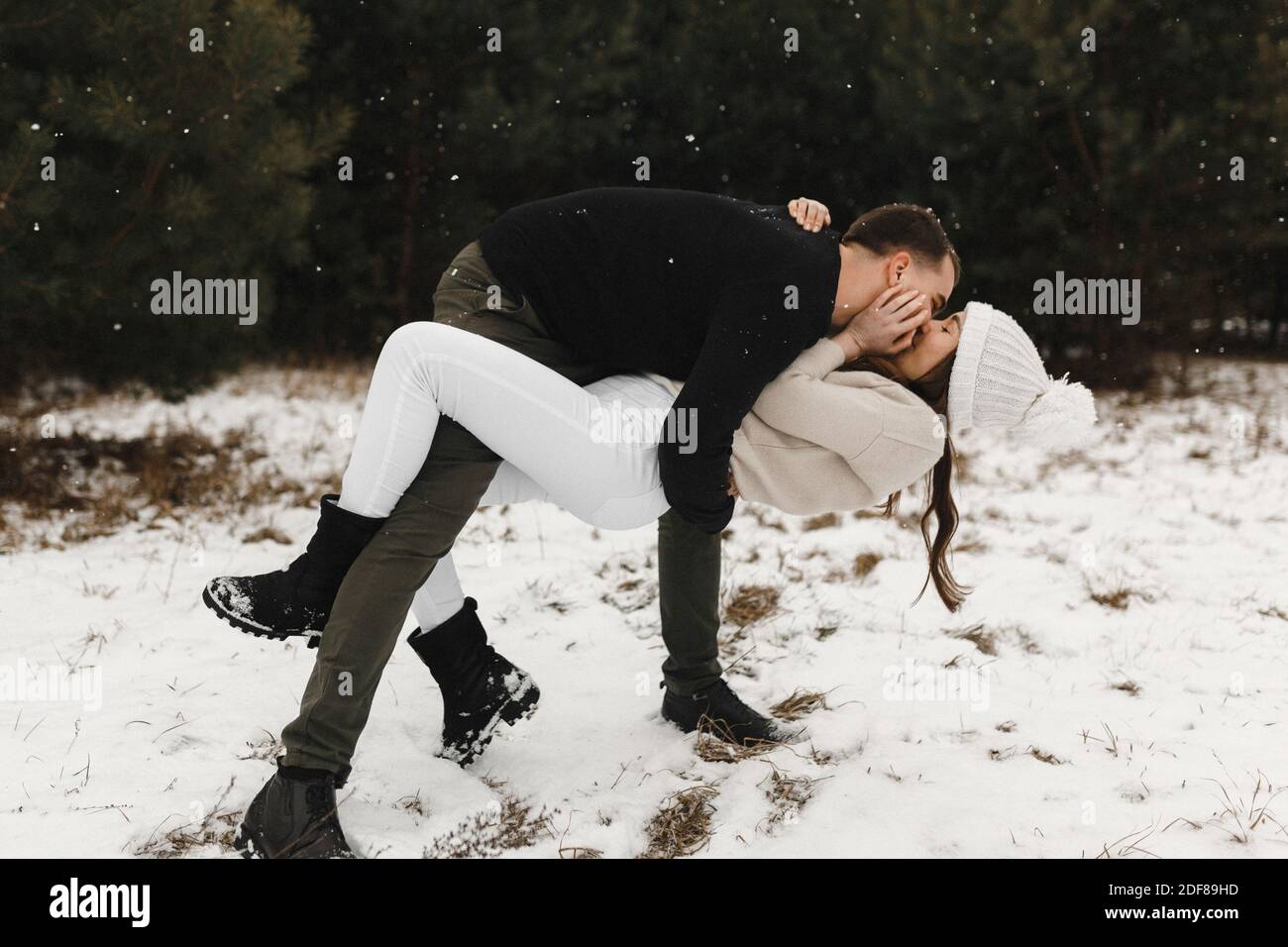 Un jeune couple embrasse dans la forêt d'hiver. Temps de neige. Les amoureux s'amusent sur la neige. Amour, relation, vacances d'hiver. Idées de photo de couple d'hiver Banque D'Images