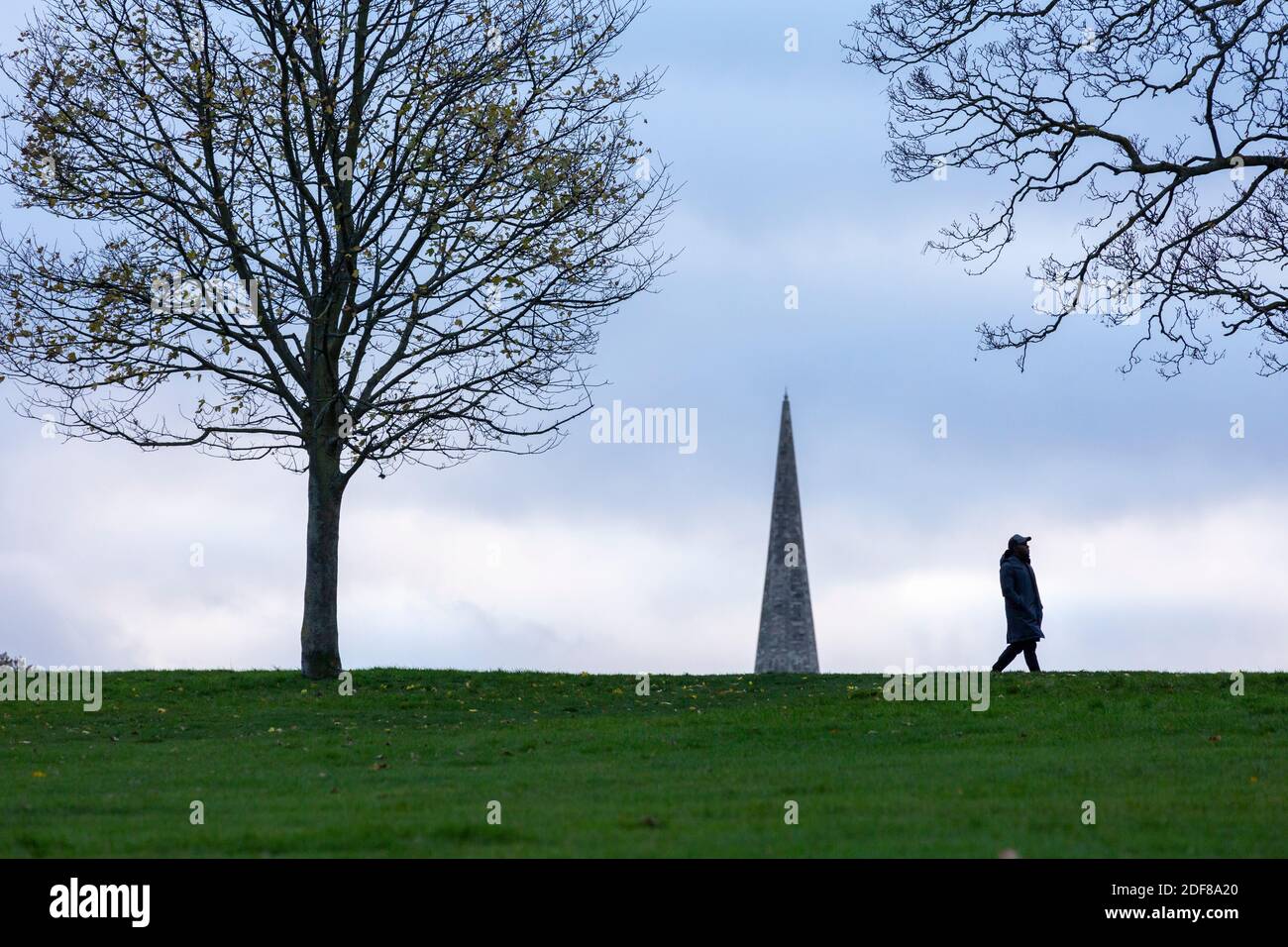 Une personne marchant dans Brockwell Park avec le clocher de l'église de la Sainte Trinité en arrière-plan, Londres Banque D'Images