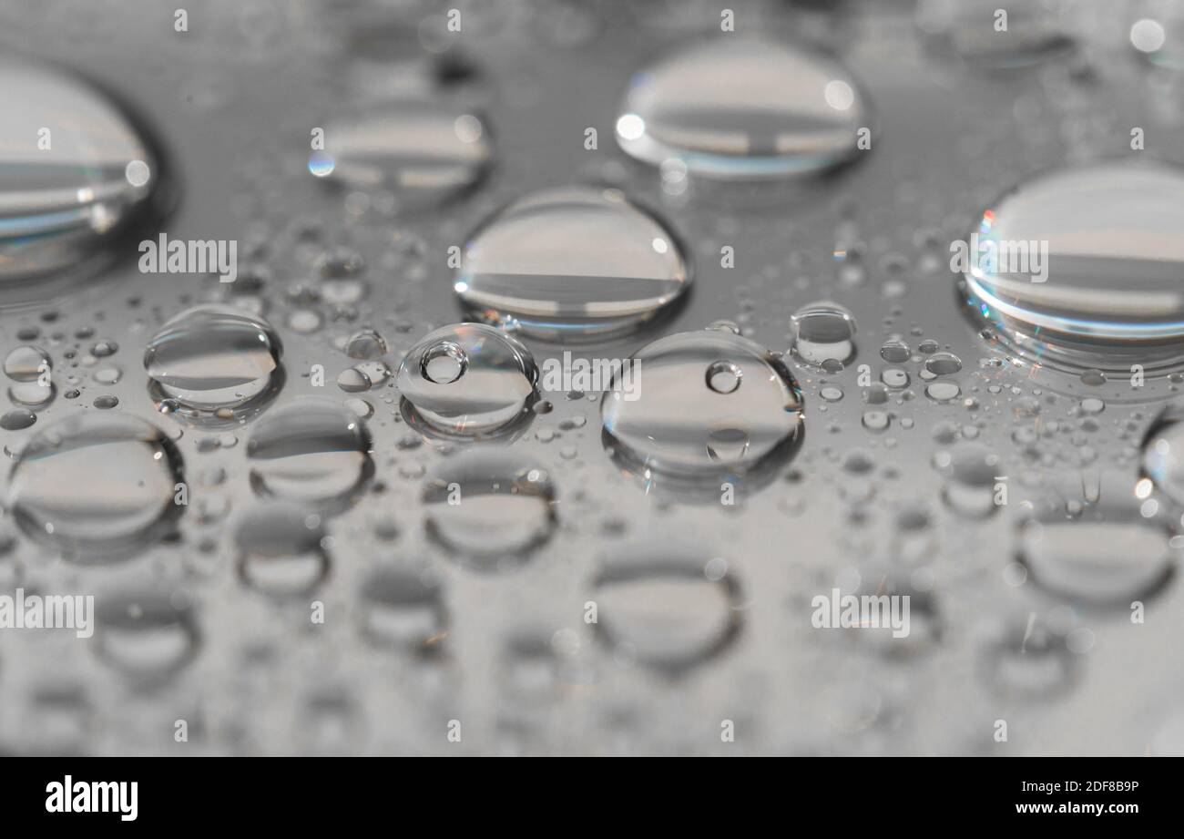 Photographie macro des gouttes d'eau sur une surface réfléchissante. Banque D'Images
