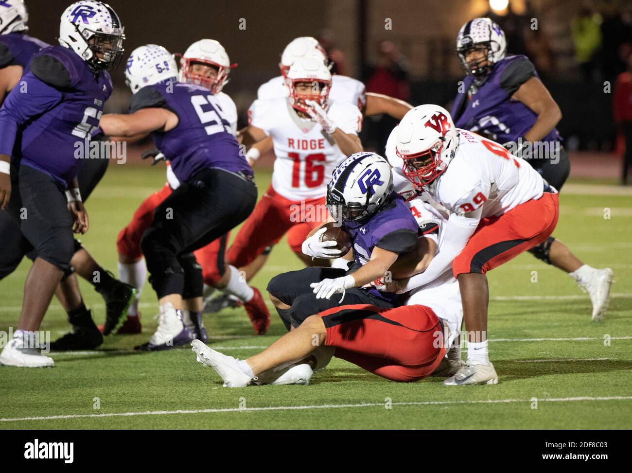 Dylan Morello (12) de Cedar Ridge est enveloppé par la défense de Vista Ridge au début du troisième trimestre, alors que Cedar Park Vista Ridge (blanc) remporte une victoire décisive sur Round Rock Cedar Ridge (bleu) dans un match de football de niveau secondaire District 25 6A au Dragon Stadium de Round Rock. Vista Ridge a gagné, 38-24. Banque D'Images