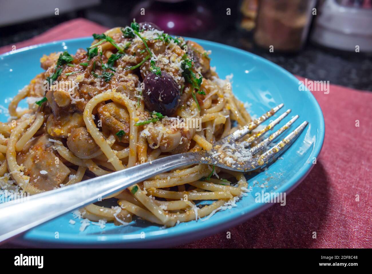 Plat typiquement italien : une généreuse portion de spaghetti à la sauce aux champignons dans une assiette bleue Banque D'Images