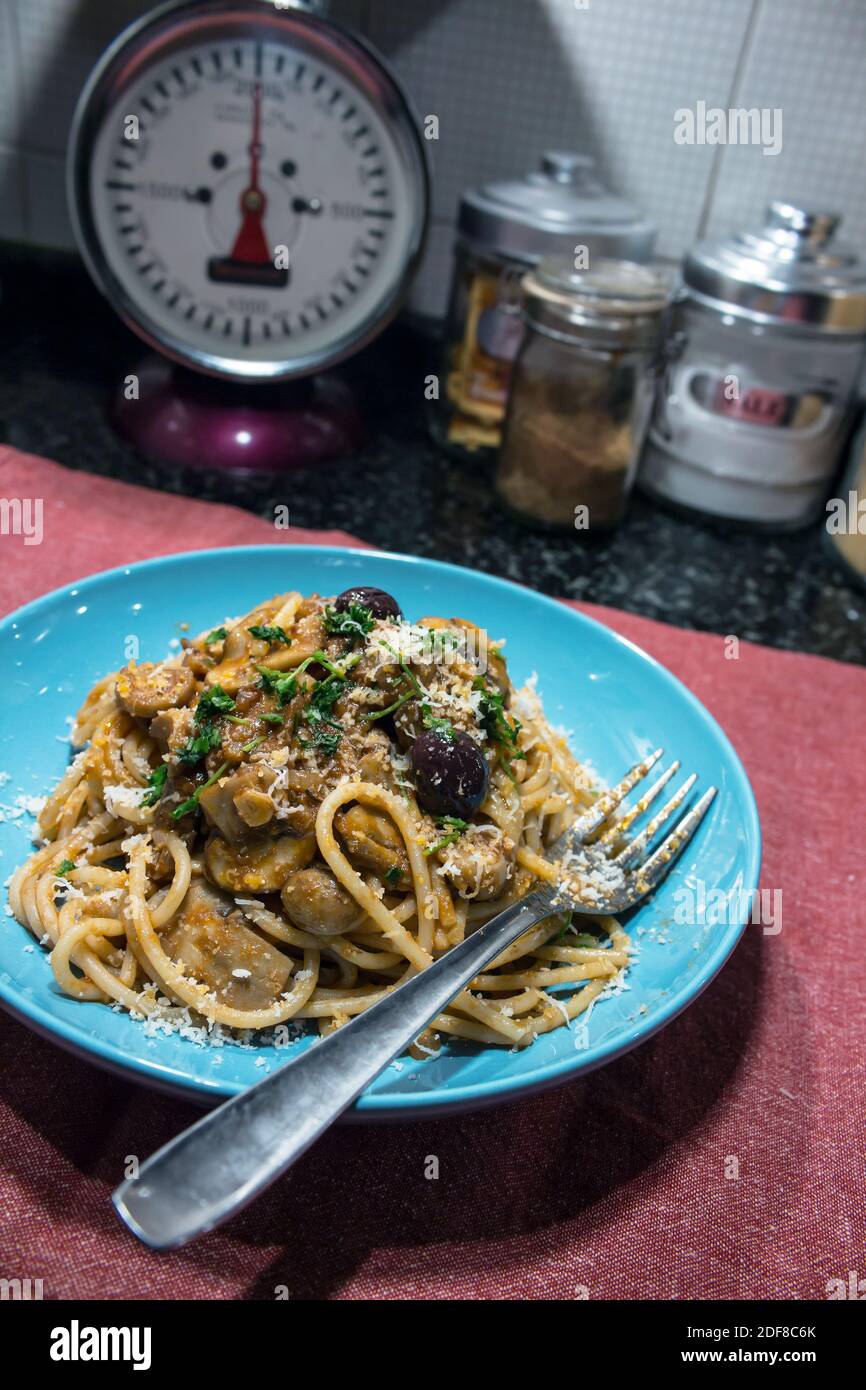 Plat typiquement italien : une généreuse portion de spaghetti à la sauce aux champignons dans une assiette bleue Banque D'Images