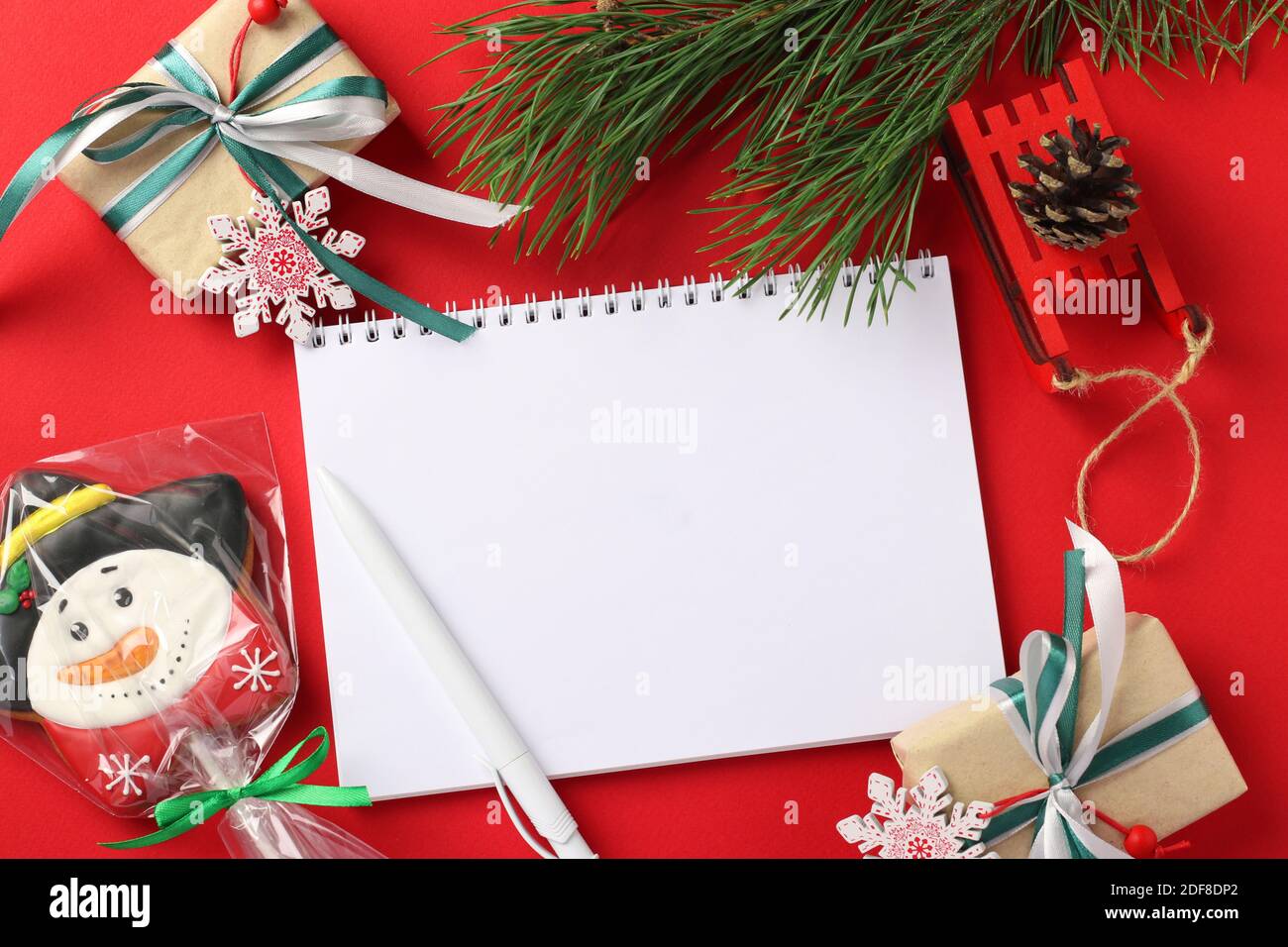 Lettre vierge de Noël pour le Père Noël avec pain d'épice formes bonhomme de neige et cadeaux sur rouge. Vue de dessus Banque D'Images