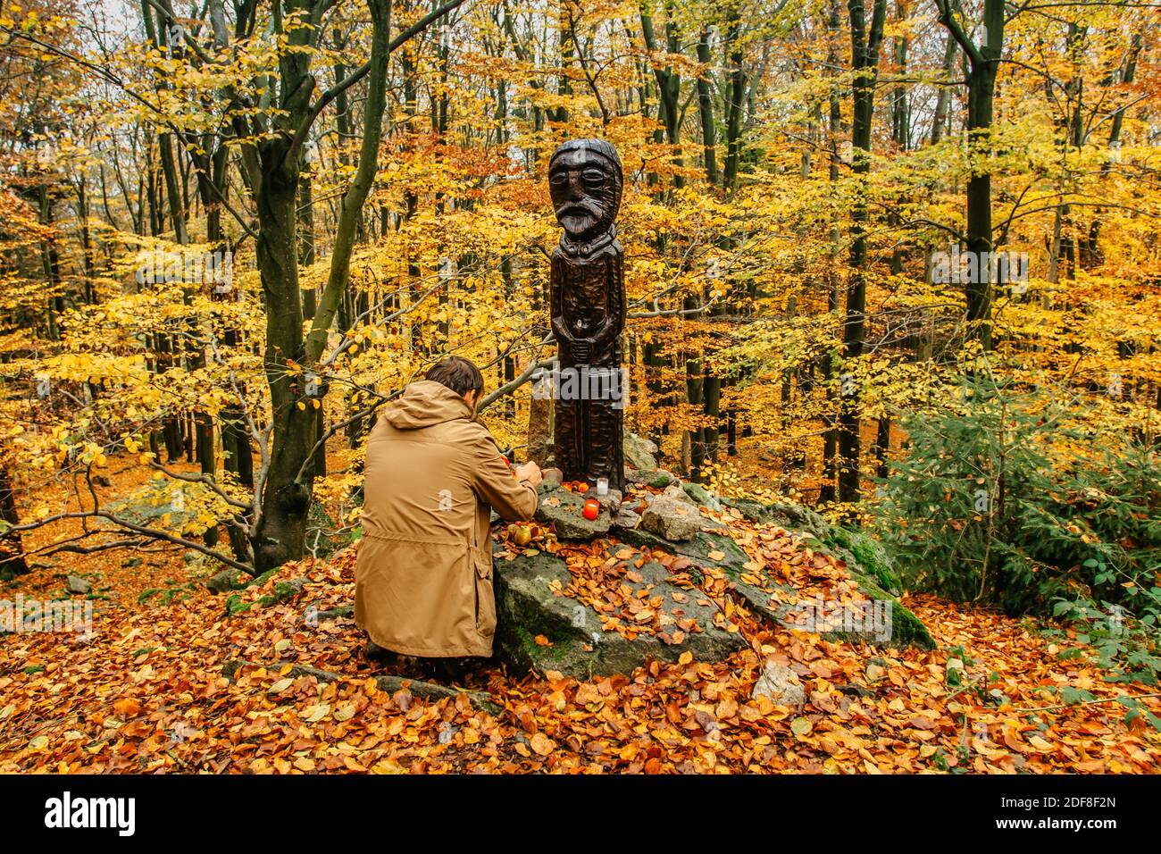 Homme priant à la statue en bois. Voyage style de vie relaxation spirituelle méditant émotionnel concept.vacances en plein air harmonie avec le paysage de la nature d'automne Banque D'Images