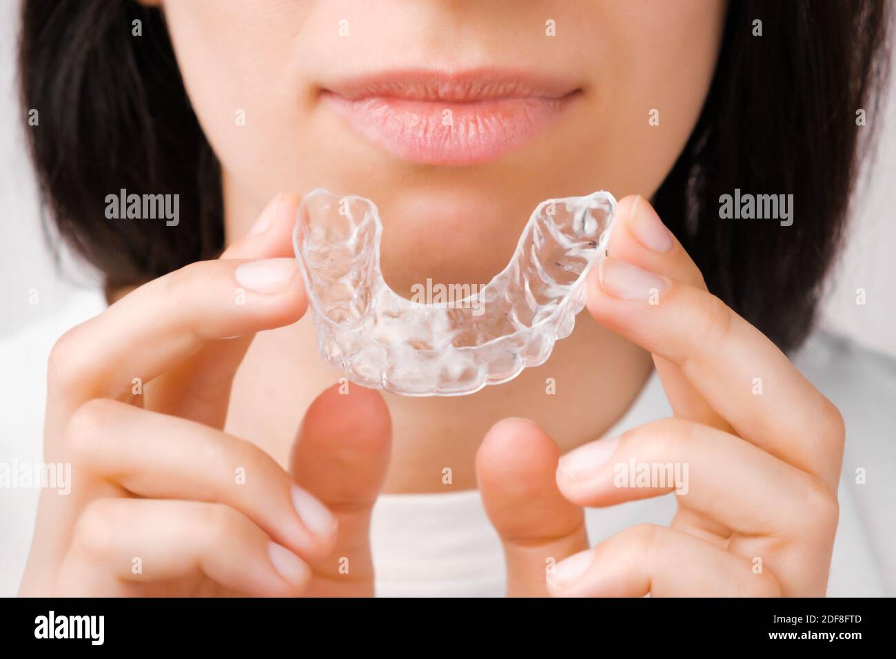 Femme souriante avec des dents parfaites et saines utilisant des bretelles amovibles ou un outil d'alignement pour lisser et blanchir les dents. Traitement orthodontique pour Banque D'Images