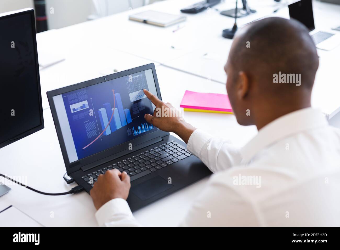 Homme de course mixte travaillant dans un bureau créatif, vérifiant les données sur un ordinateur portable Banque D'Images