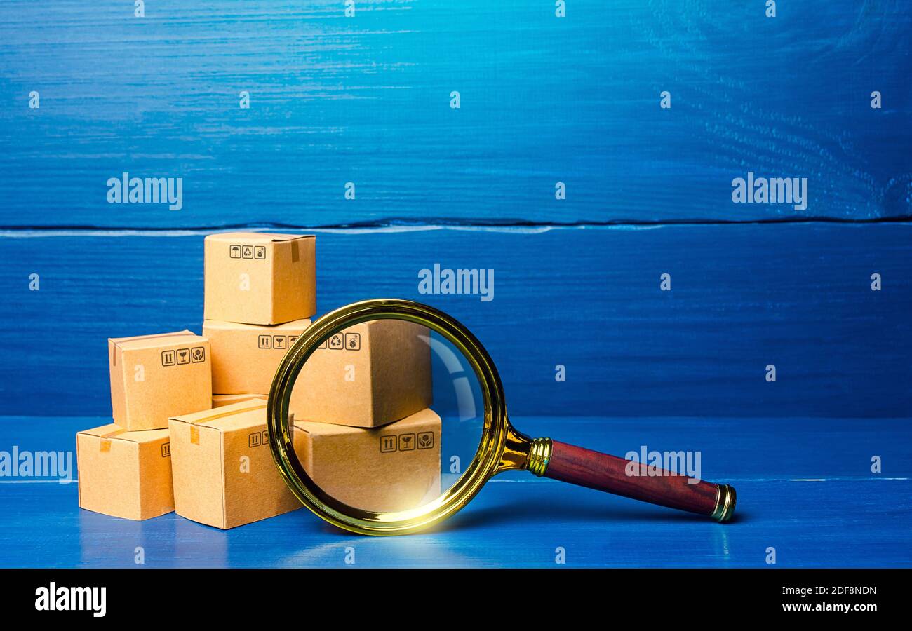 Boîtes en carton et loupe. Concept de recherche de biens et de composants. Vérification des achats. Contrôle qualité. Offre et demande, distributi Banque D'Images