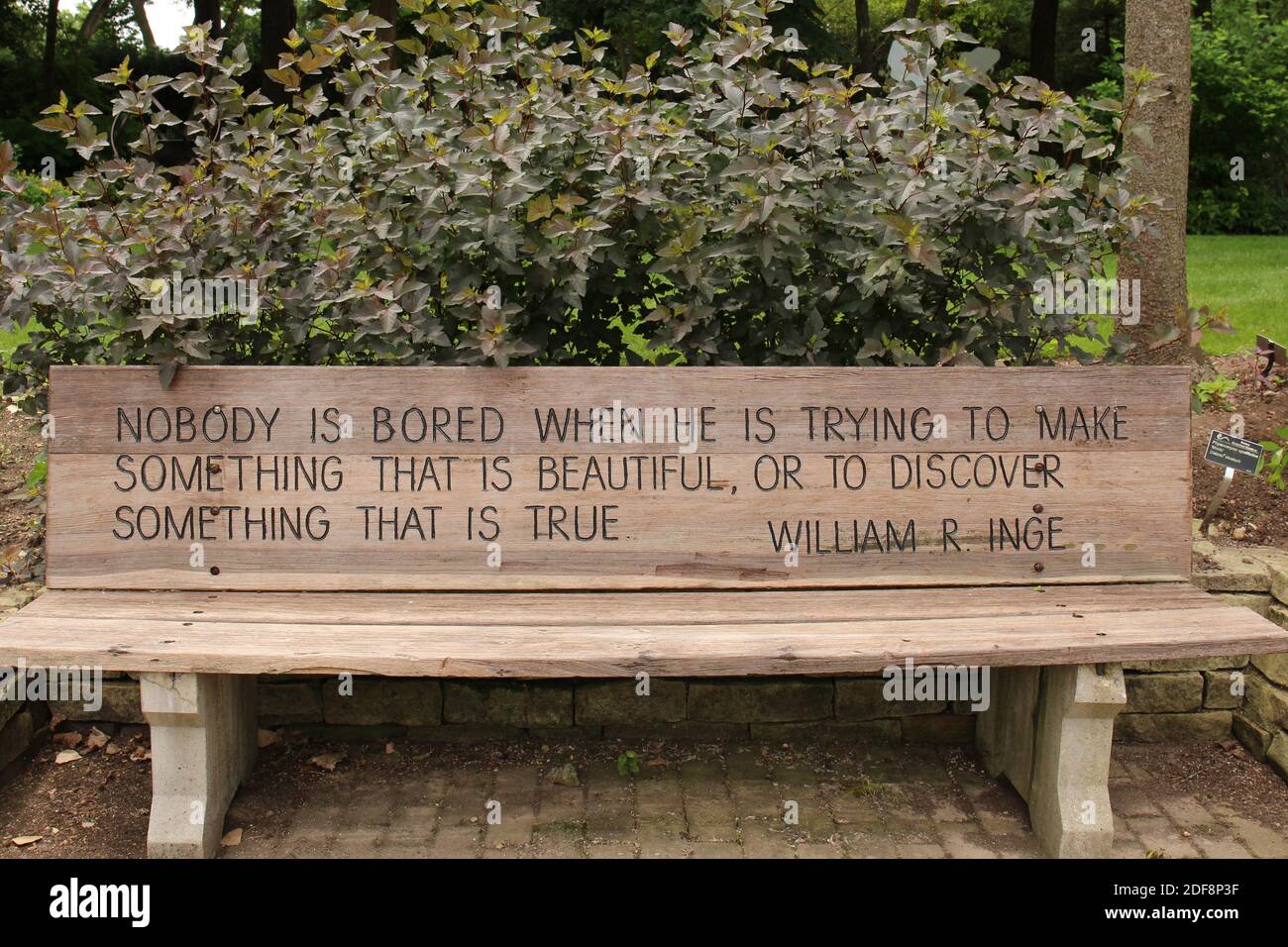 Un banc de parc en bois gravé avec une citation inspirante le long d'un mur  de soutènement de pierre, arbustes, arbres aux jardins botaniques Rotary à  Janesville, Wisconsin Photo Stock - Alamy