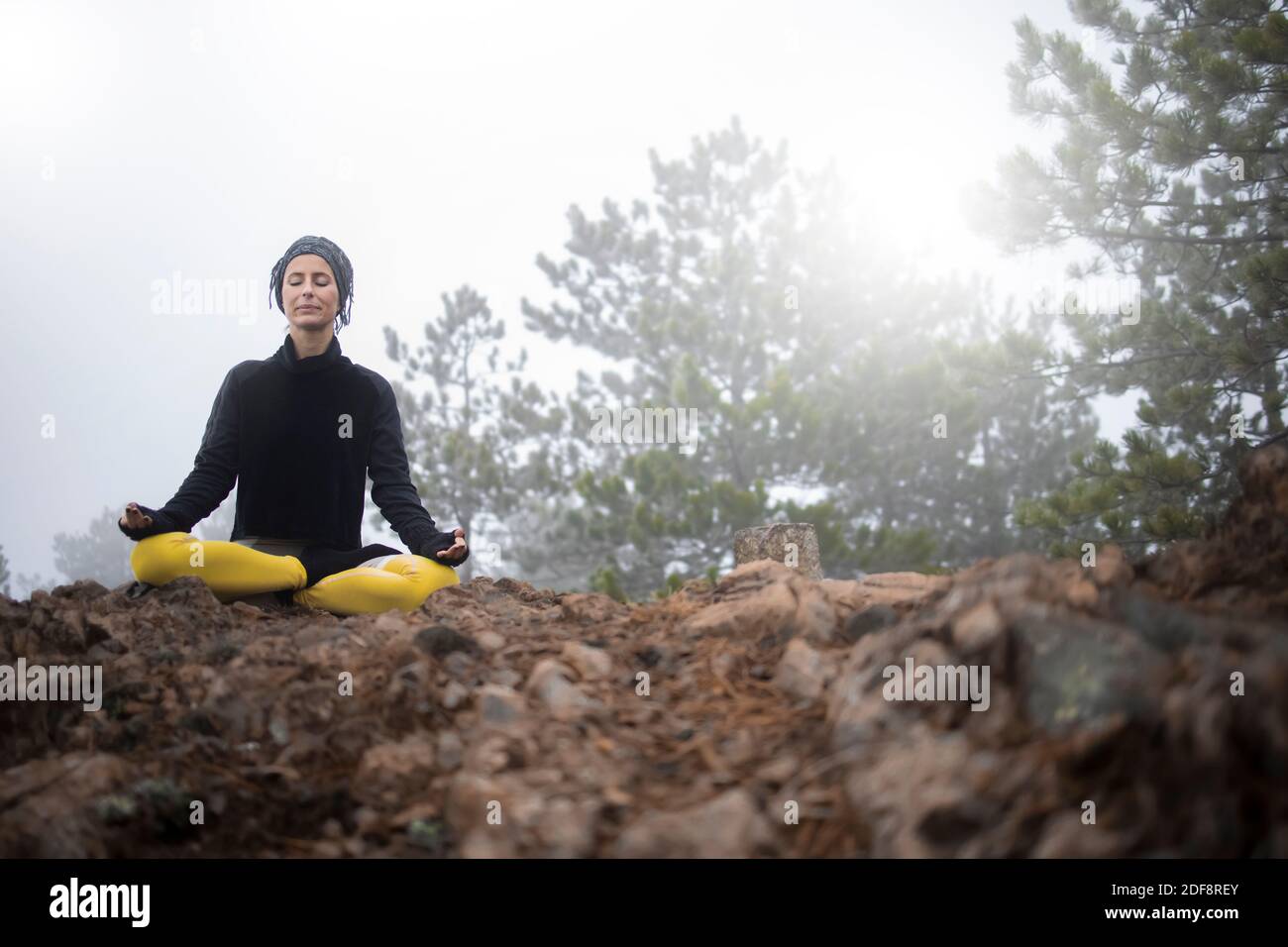 Femme méditant et pratiquant le yoga au sommet de la montagne Banque D'Images