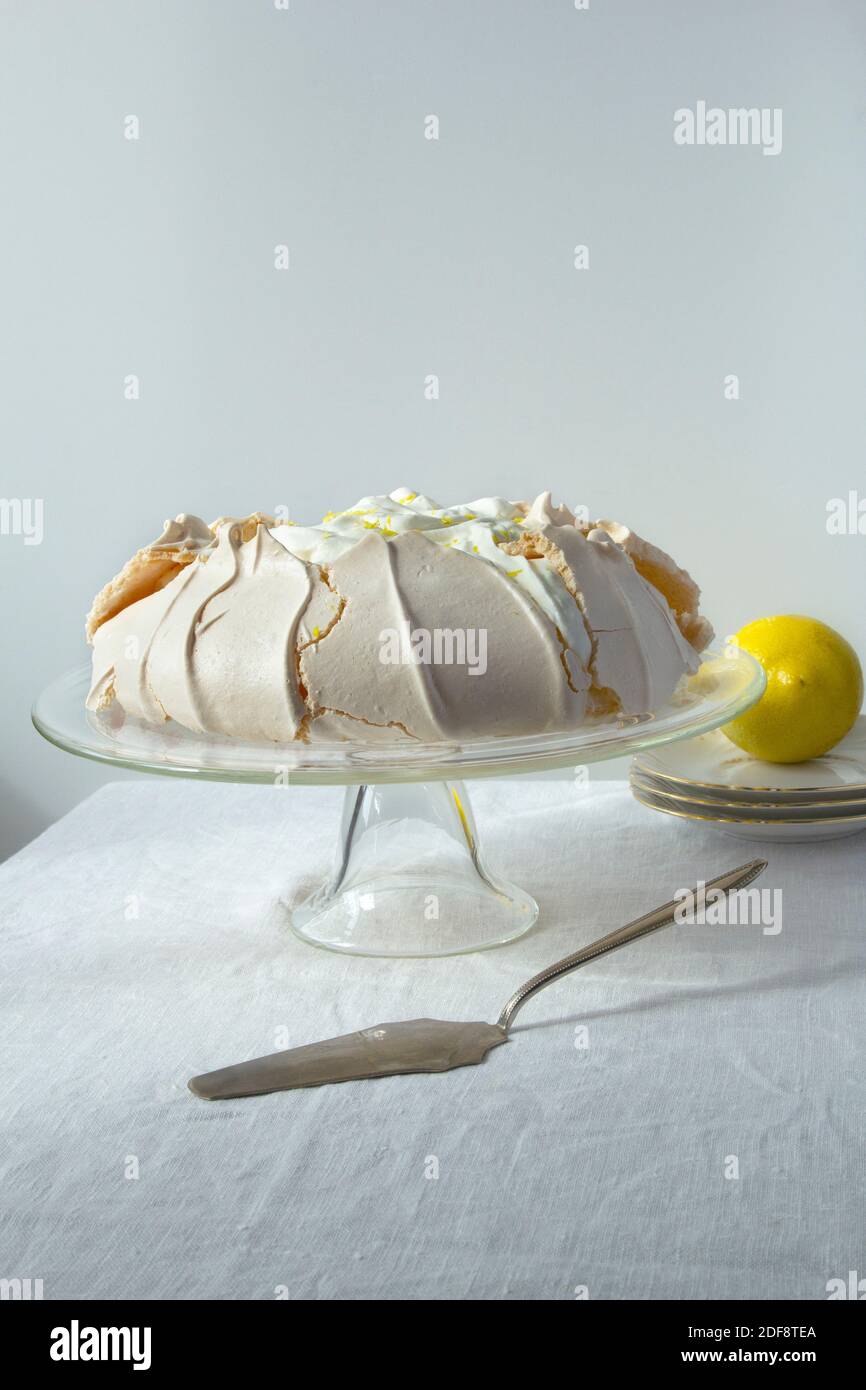 Gâteau à la meringue maison Pavlova avec crème fouettée et citron support à gâteau en verre sur fond clair Banque D'Images