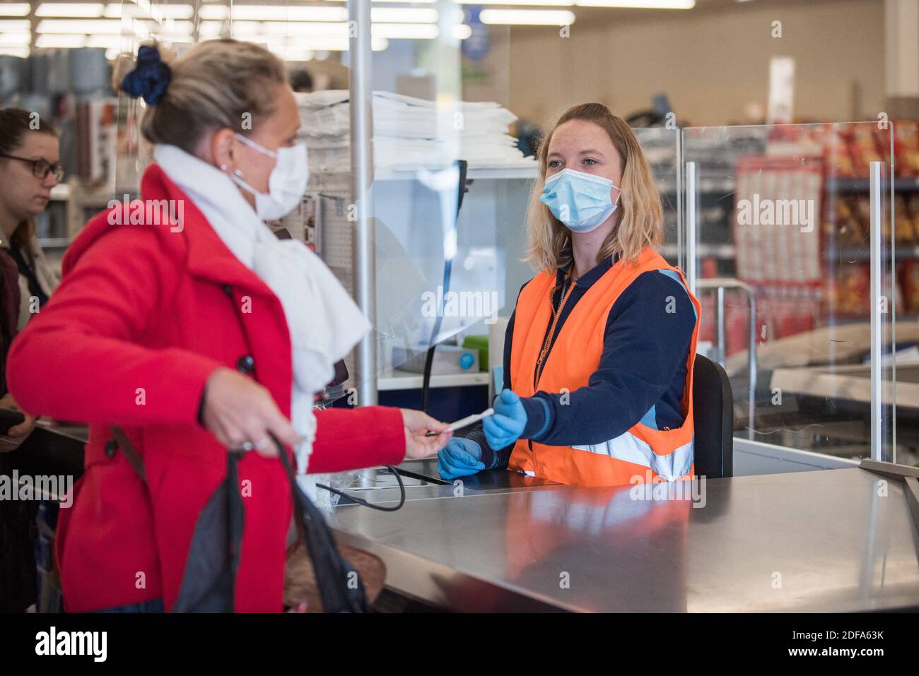 Une caissière remet son reçu à un client dans un supermarché action le 15  mai 2020 à Lambres-lez-Douai près de Lens, après l'entrée en vigueur d'une  levée partielle des restrictions dues à