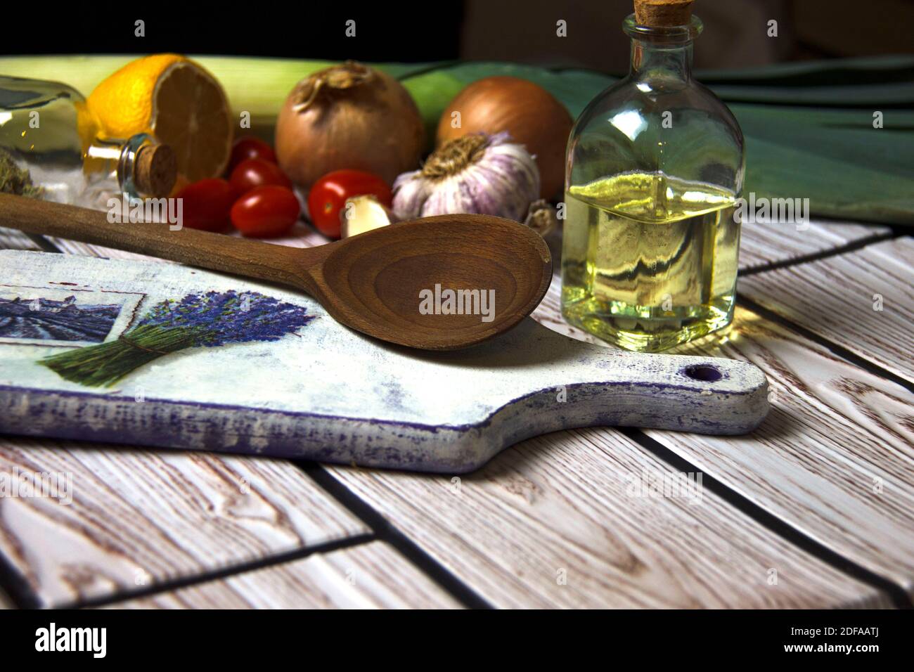 Fond de cuisson. Huile dans une bouteille, ail, oignon, tomates et citron sur une planche à découper. Préparation des aliments. Concept de saine alimentation. Banque D'Images