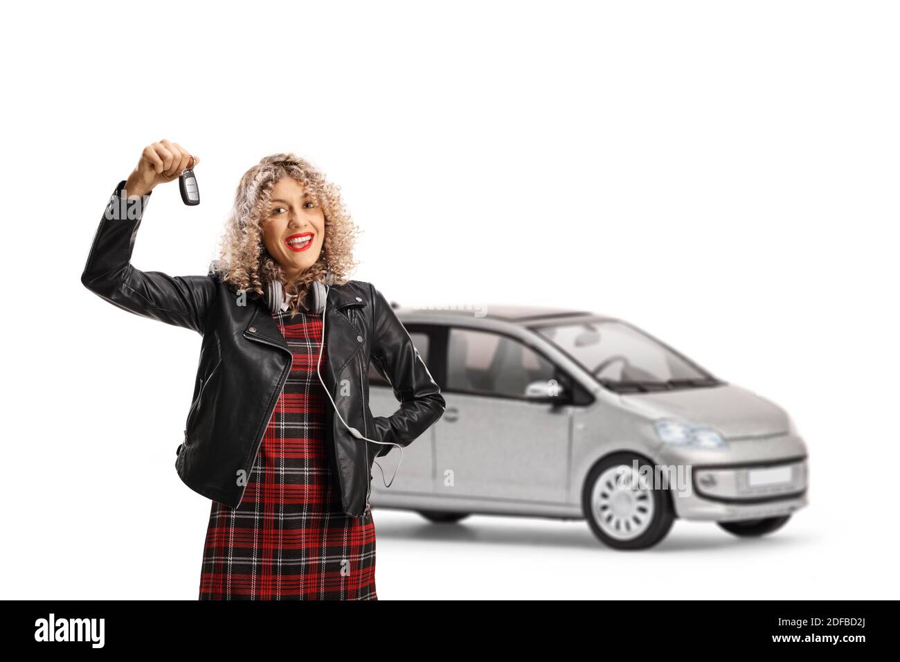 Jeune femme dans une veste en cuir tenant une clé de une petite voiture urbaine isolée sur fond blanc Banque D'Images