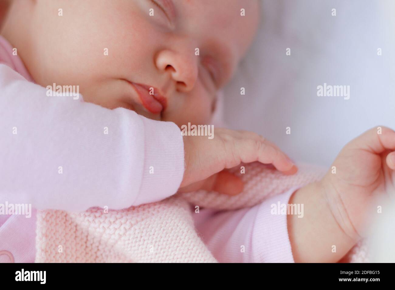 Nouveau-né bébé fille portant un costume rose dormir dans un berceau à l'extérieur Banque D'Images