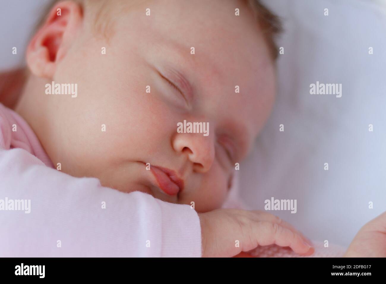 Nouveau-né bébé fille portant un costume rose dormir dans un berceau à l'extérieur Banque D'Images