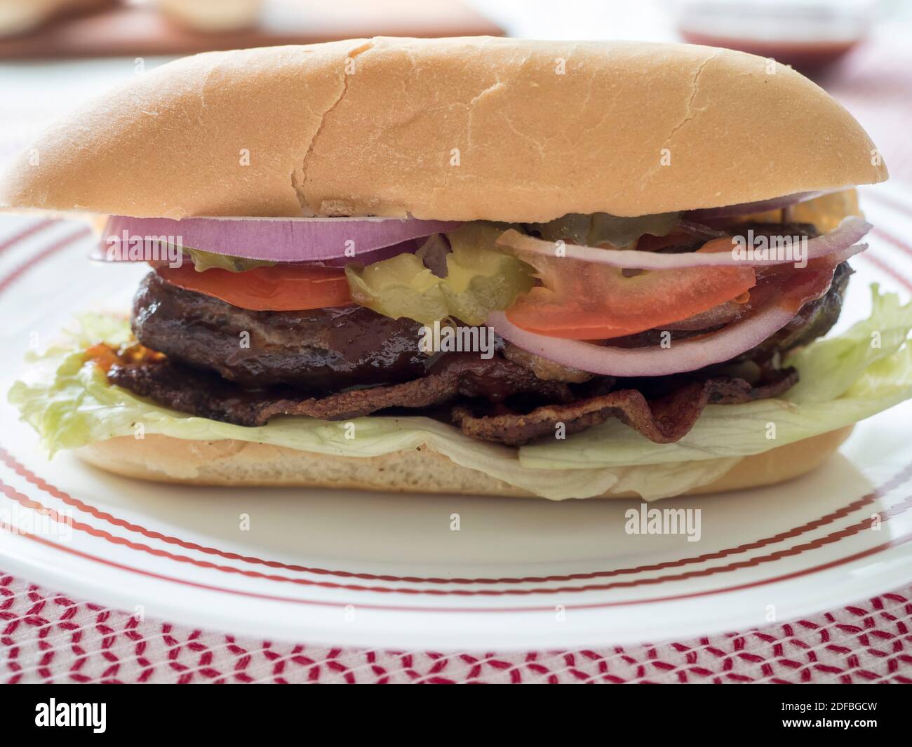 Gros plan directement sur la vue d'un cheeseburger farci sur un pain de cagoule, recouvert de légumes et de sauce, également connu sous le nom de lucy juteuse Banque D'Images