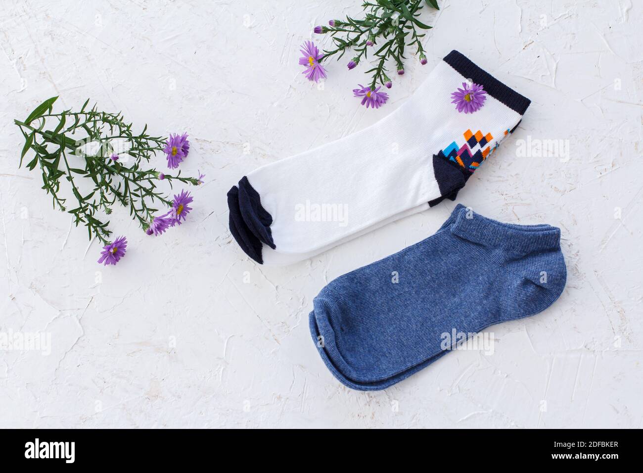 Deux paires de chaussettes et de fleurs pour femmes sur fond blanc structuré, vue du dessus. Banque D'Images