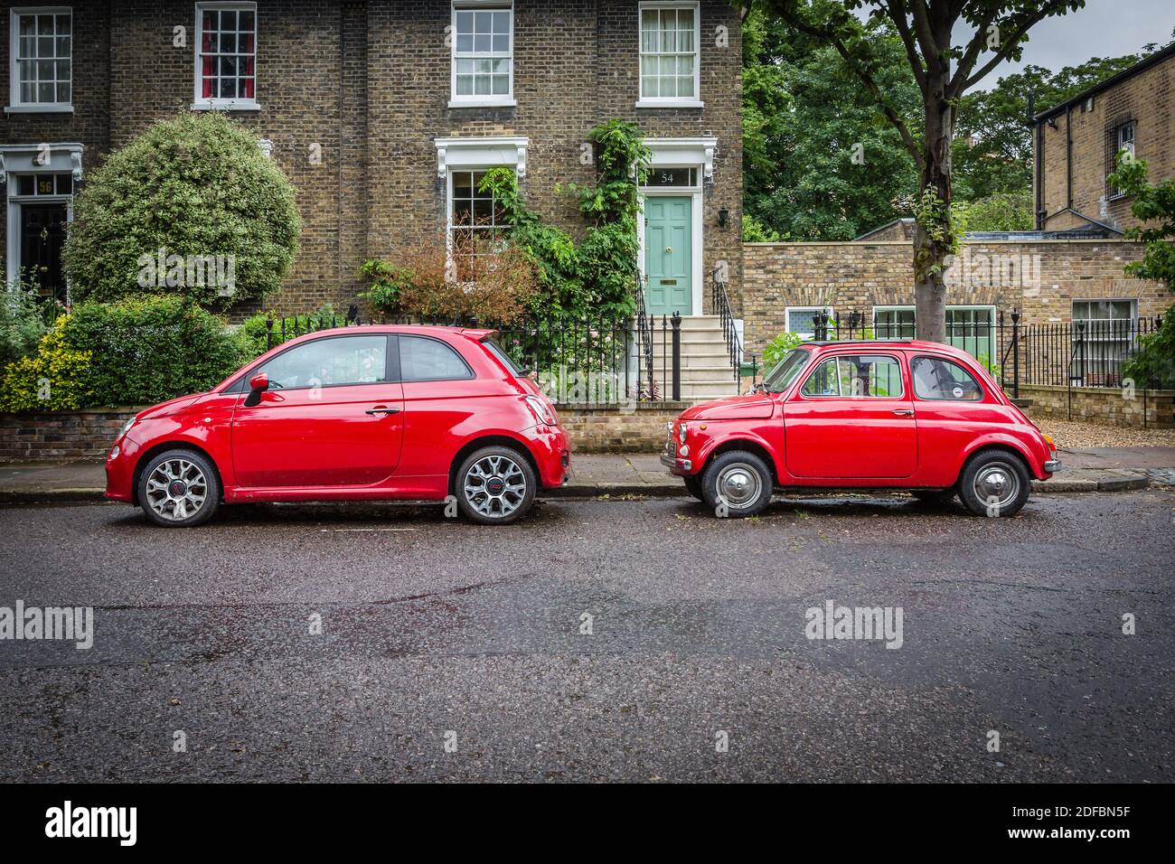 Deux générations de la Fiat 500 dans la même couleur rouge garées sur une rue verdoyante de Londres. Banque D'Images