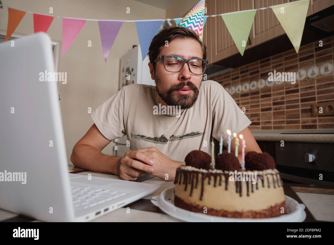 Homme célébrant son anniversaire en ligne en temps de quarantaine. Guy  célébrant son anniversaire , soufflant la bougie sur le gâteau d'anniversaire  et de faire un appel vidéo Photo Stock - Alamy