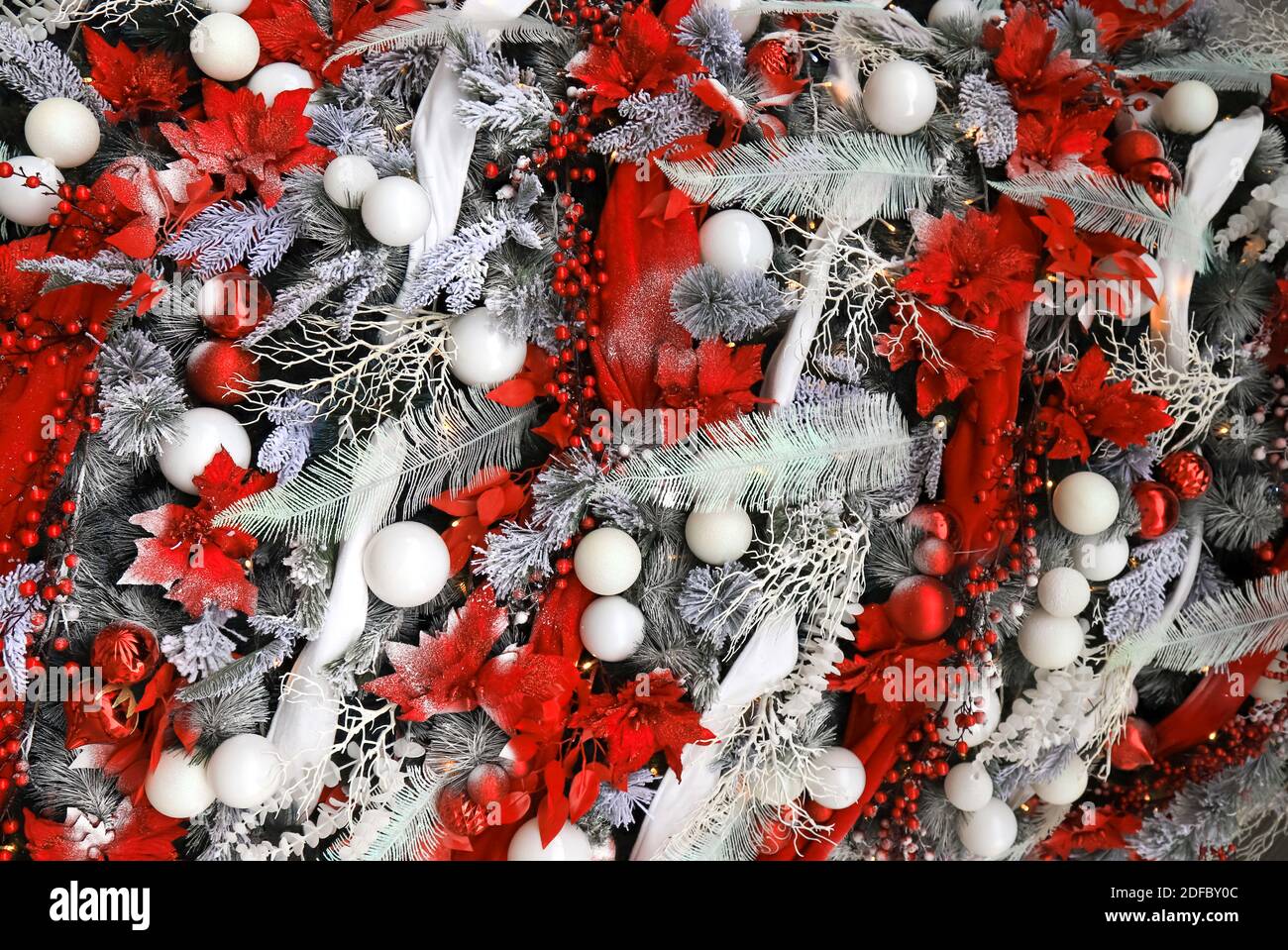 Arbre de Noël exceptionnellement joliment décoré avec des branches et des fleurs rouges, des boules et des guirlandes. Nouvel an vacances d'hiver, jouets, décorations Banque D'Images