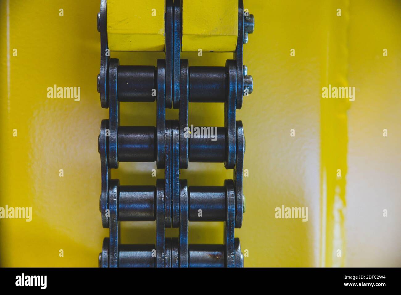 Une chaîne à rouleaux à double rangée sur fond jaune Banque D'Images