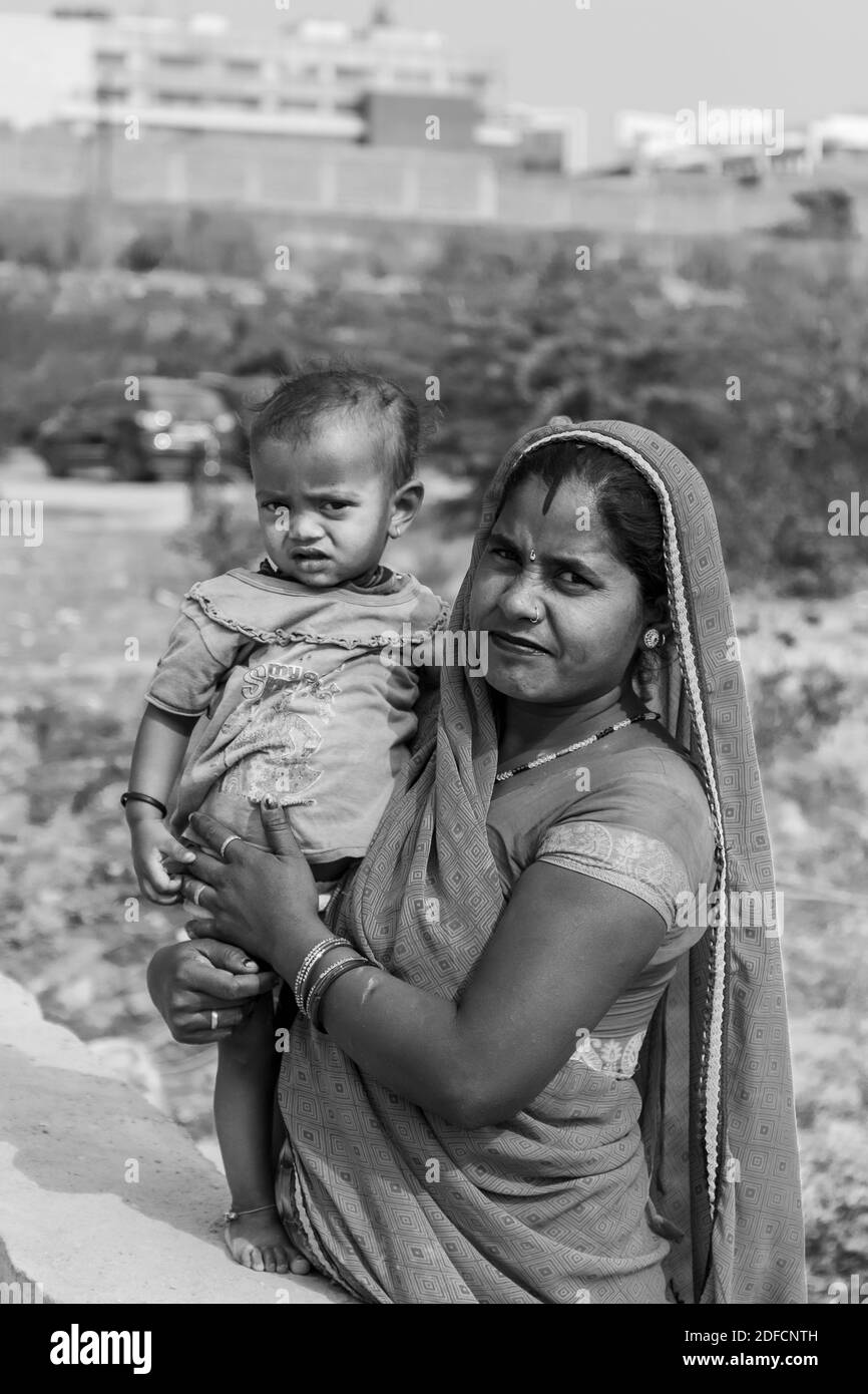 NOIDA, UTTAR PRADESH, INDE - NOVEMBRE 2020 : Portrait d'une femme indienne de la région du village avec son enfant debout sur le terrain ouvert de l'école à Sari. Banque D'Images