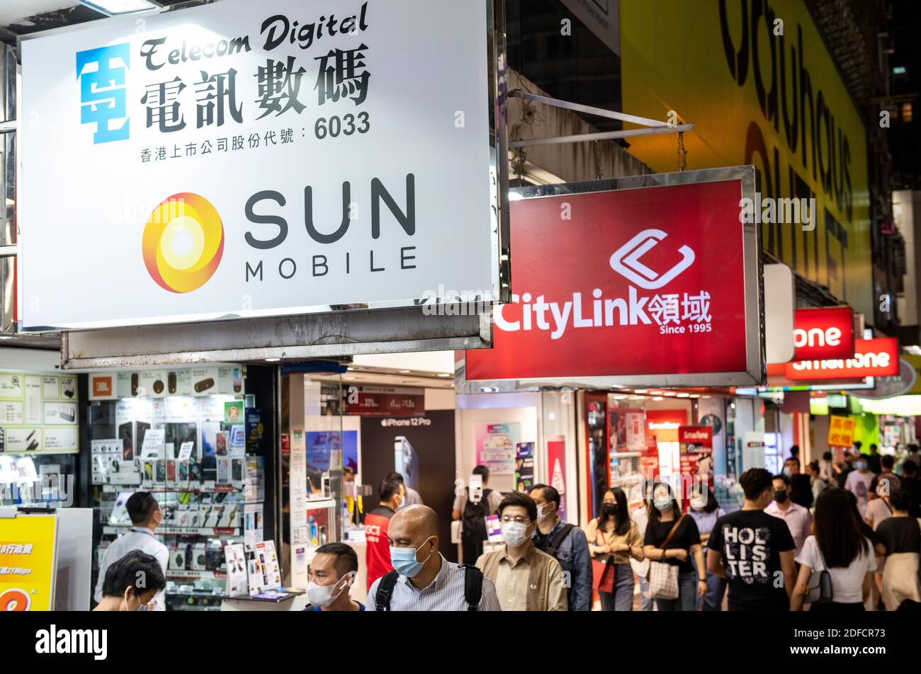 Des piétons marchent devant plusieurs sociétés de télécommunications Sun Mobile, Citylink, magasins de Vodaphone à Hong Kong. Banque D'Images