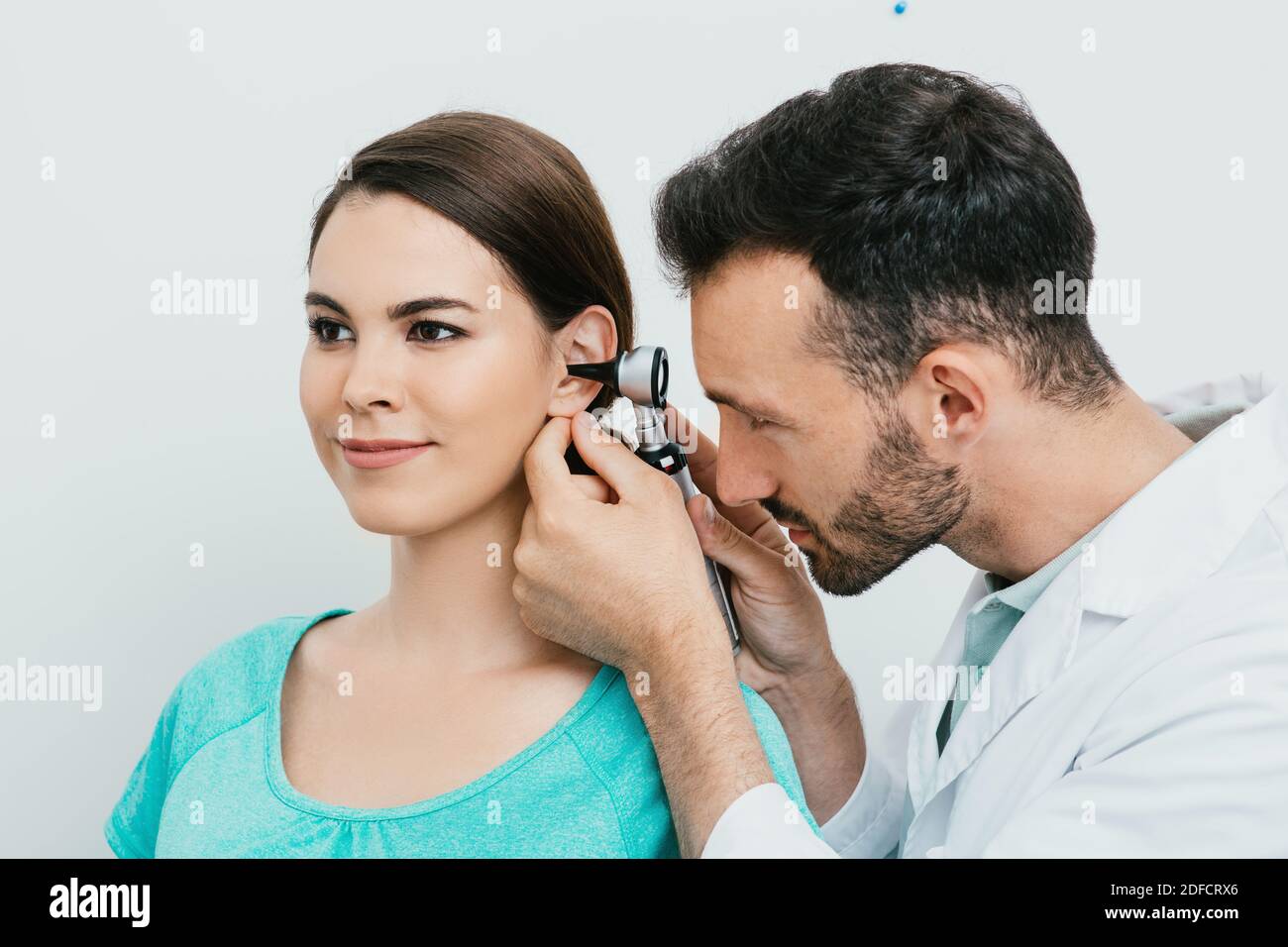 Otolaryngologiste vérifiant l'oreille femelle adulte à l'aide d'un otoscope. Examen d'audition pour femme hispanique. Otite moyenne, inflammation de l'oreille Banque D'Images