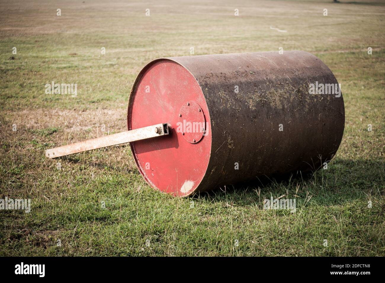 Pose de rouleau de sol du champ. Vieux rouleau de pelouse en métal rouillé sur terrain de cricket. Banque D'Images
