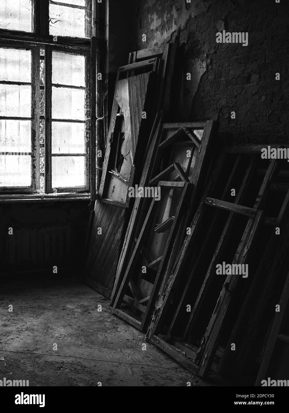 Photo en niveaux de gris de fenêtres cassées dans une créepy abandonnée chambre à l'intérieur d'un bâtiment Banque D'Images