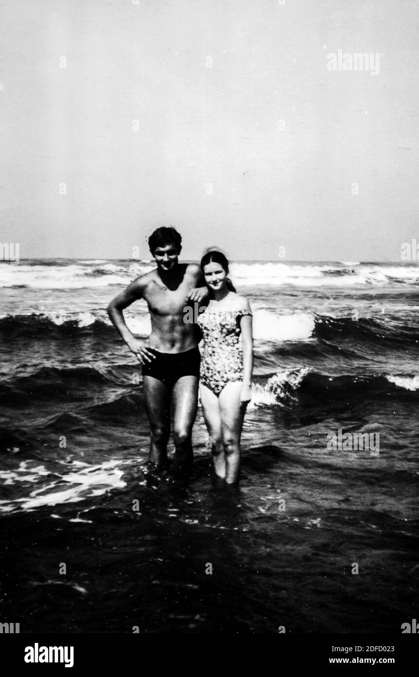 Années 1960, années 1970 Jeune couple de la mer en plein air en noir et blanc s'amuser à la plage de Castinglioncello en Toscane. Italie. Numérisation des rayures et des imperfections Banque D'Images