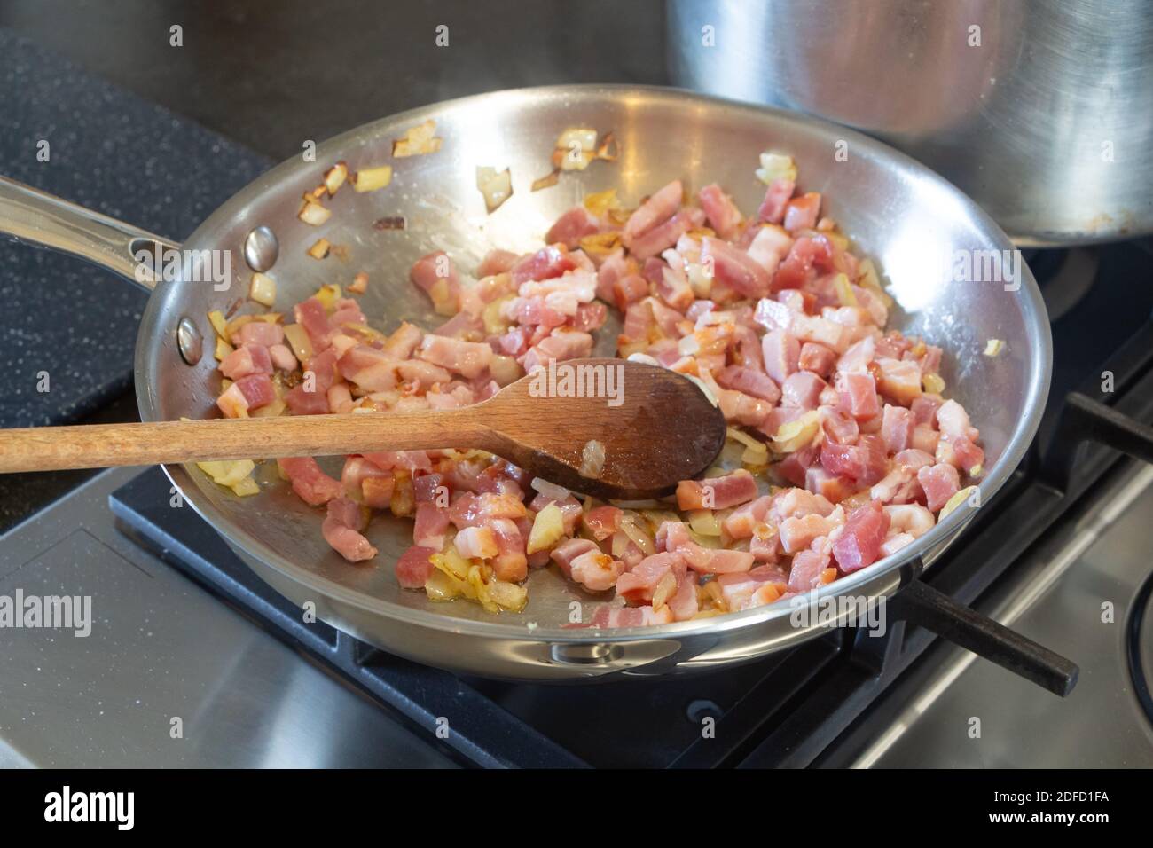 Morceaux d'oignon et cubes de bacon frits sur le cuiseur à gaz Banque D'Images