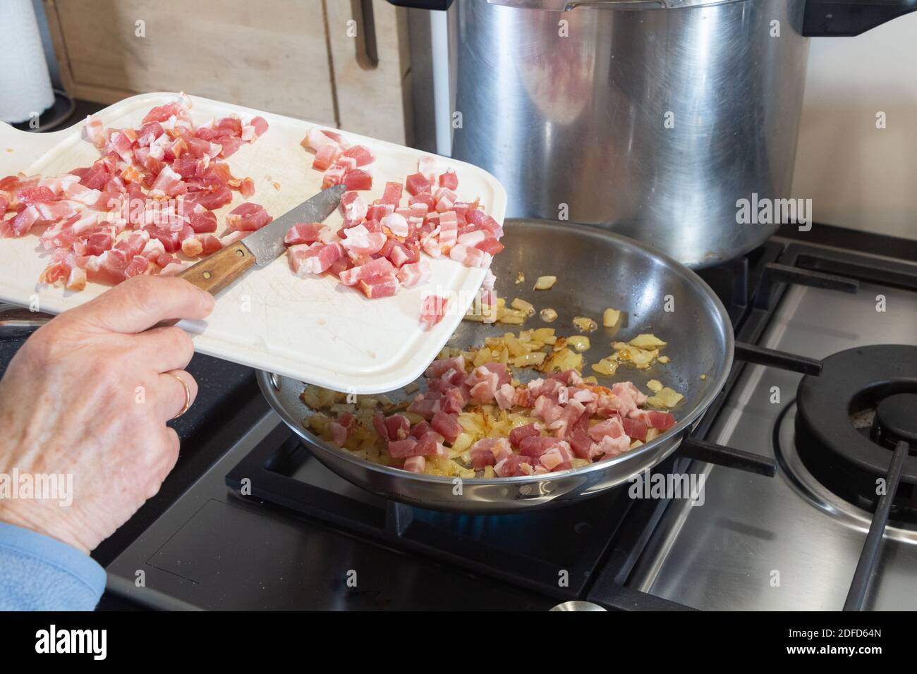 Pour mettre des cubes de bacon dans la poêle avec des oignons pièces Banque D'Images