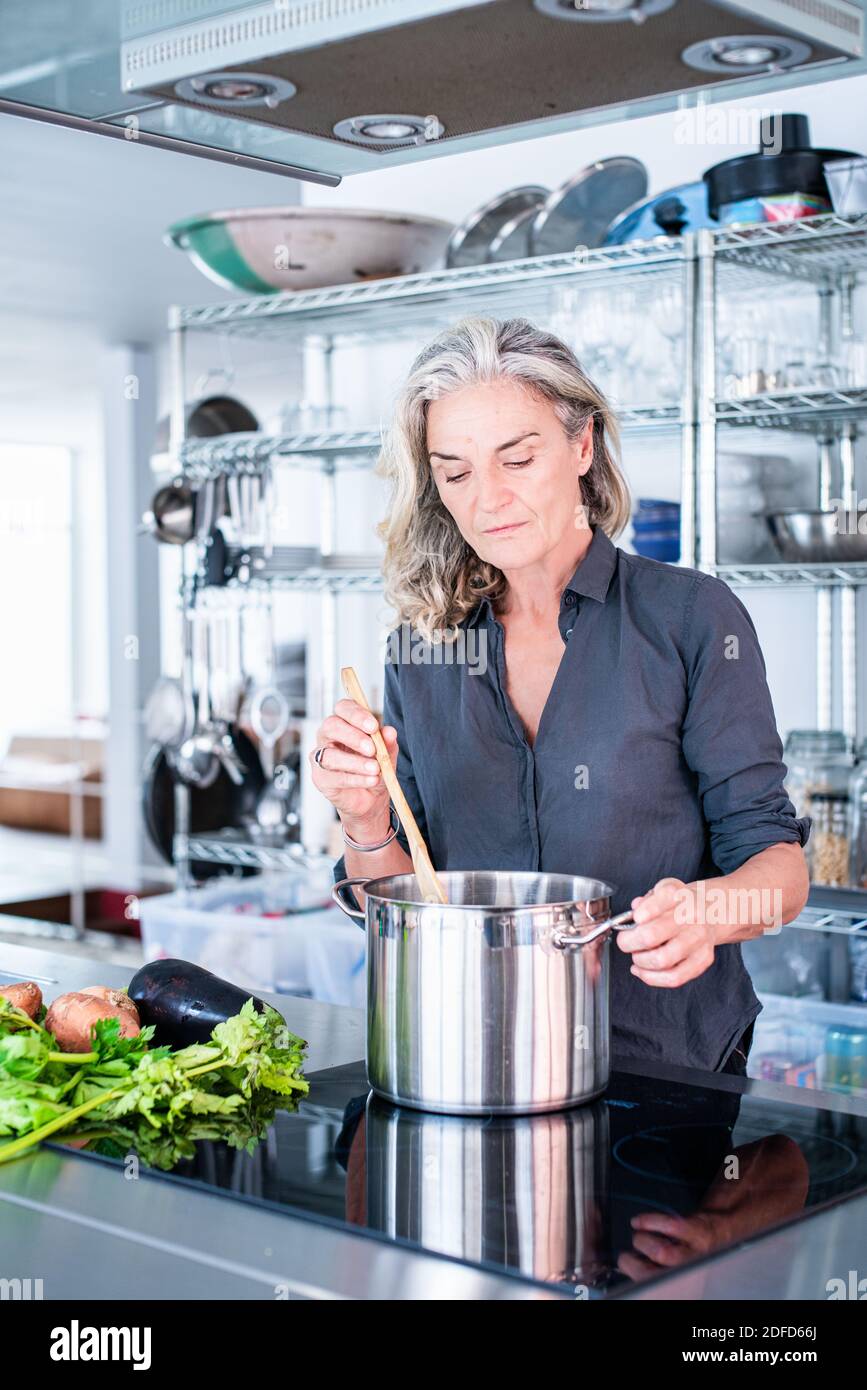 Femme cuisinant sur une table de cuisson à induction. Banque D'Images