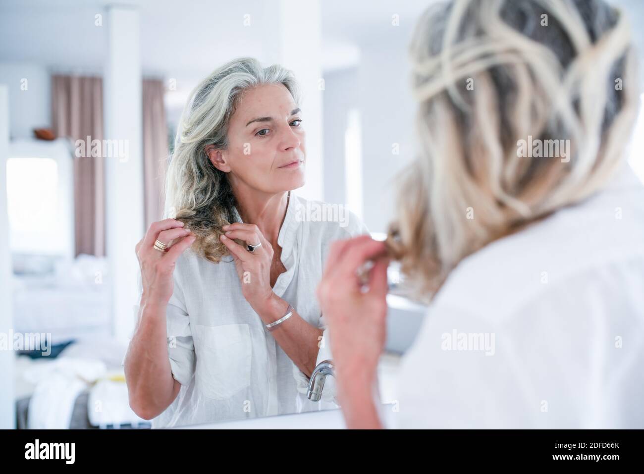 Woman inspecting la pointe de ses cheveux. Banque D'Images